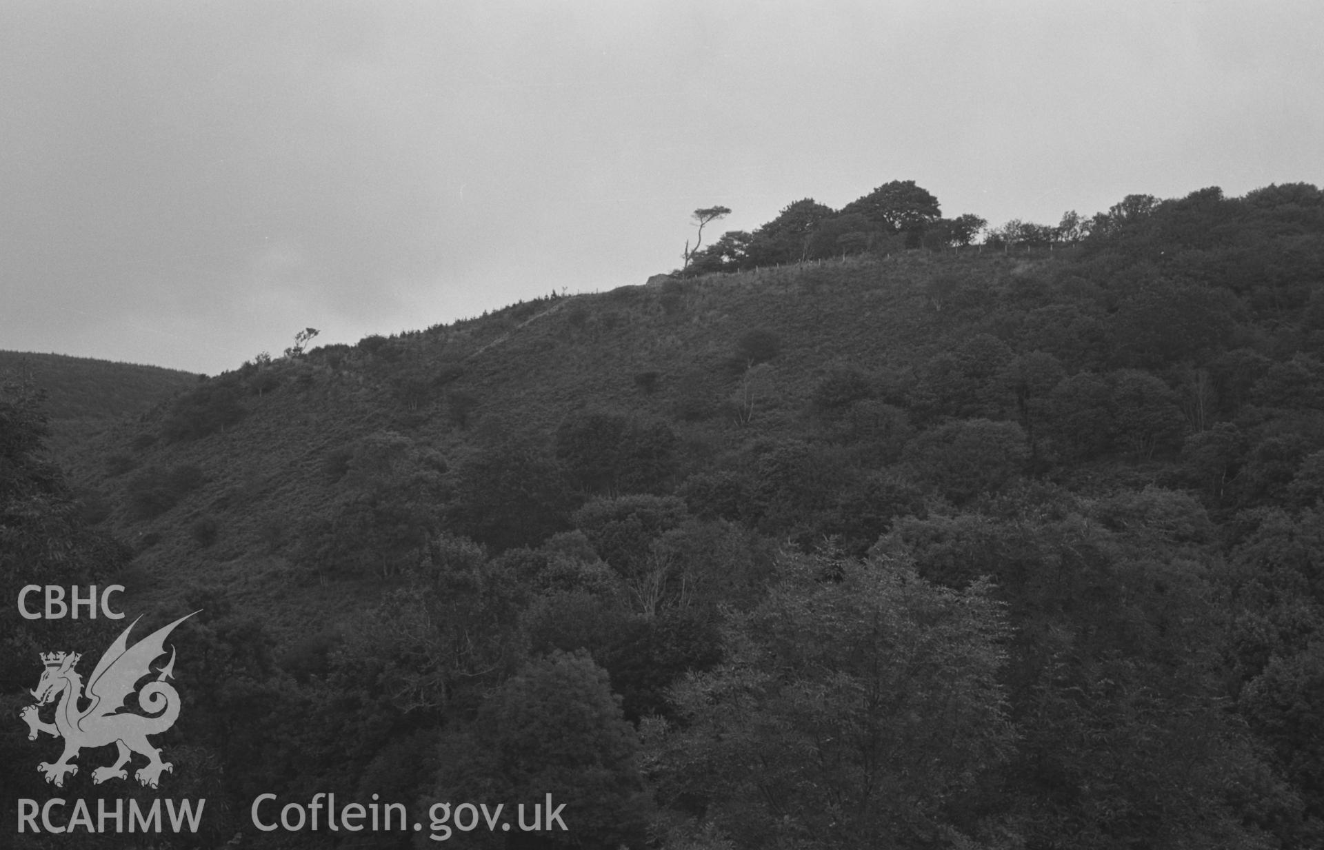 Digital copy of black & white negative showing Garn Wen iron-age camp, 2.3km east of Ffostrasol, from Pen-y-Graig farm; S.W. end of rampart, showing as drystone mound on skyline in centre of picture; wall running down slope from this is presumably a modern wall built from the stores of the ramparts. Photograph by Arthur Chater, Aug 1967. (Looking north north east from Grid Reference SN 395 468).