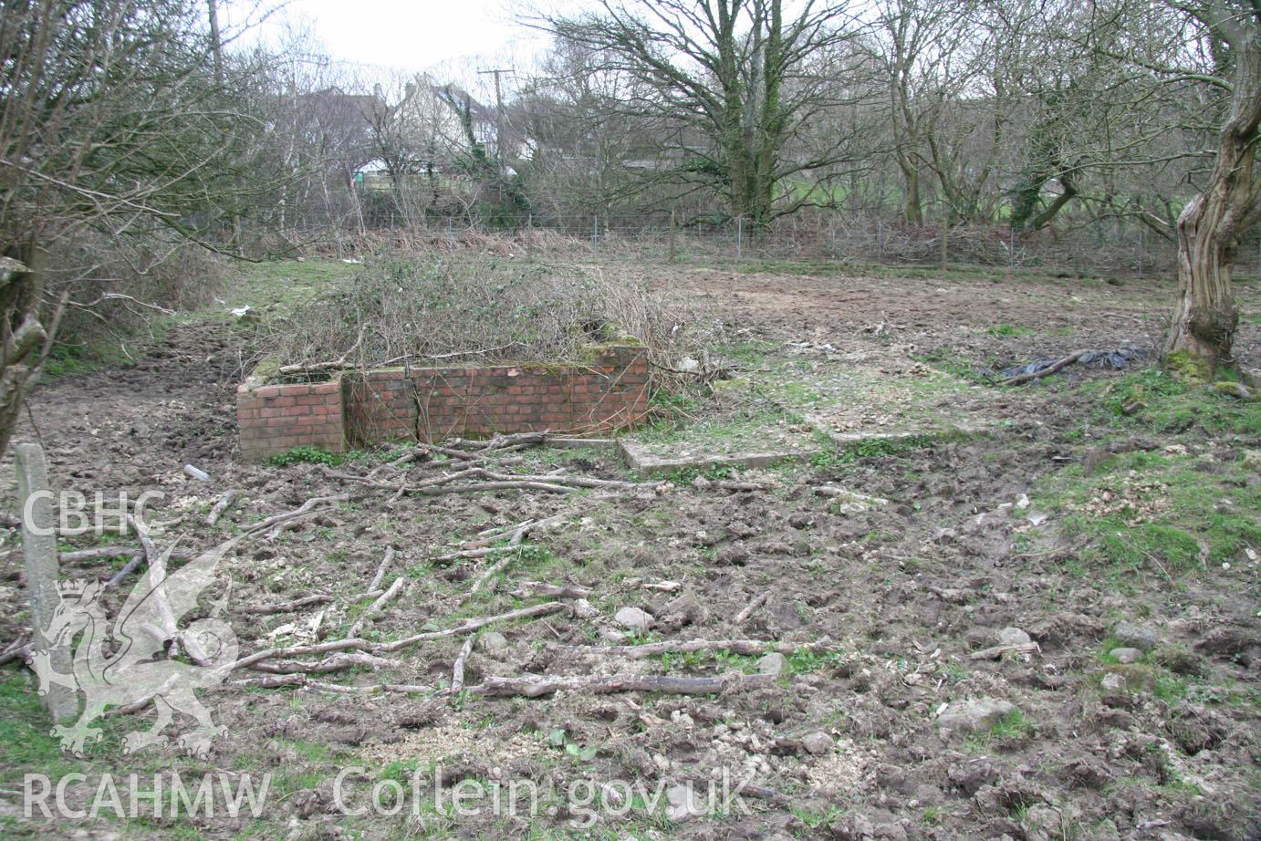 'Brick structure and concrete hard stand (looking north-northeast).' Photographed during site visit to land south of school lane, Penperlleni. Part of Archaeological Desk Based Assessment conducted by Iestyn Jones of Archaeology Wales, 2014.