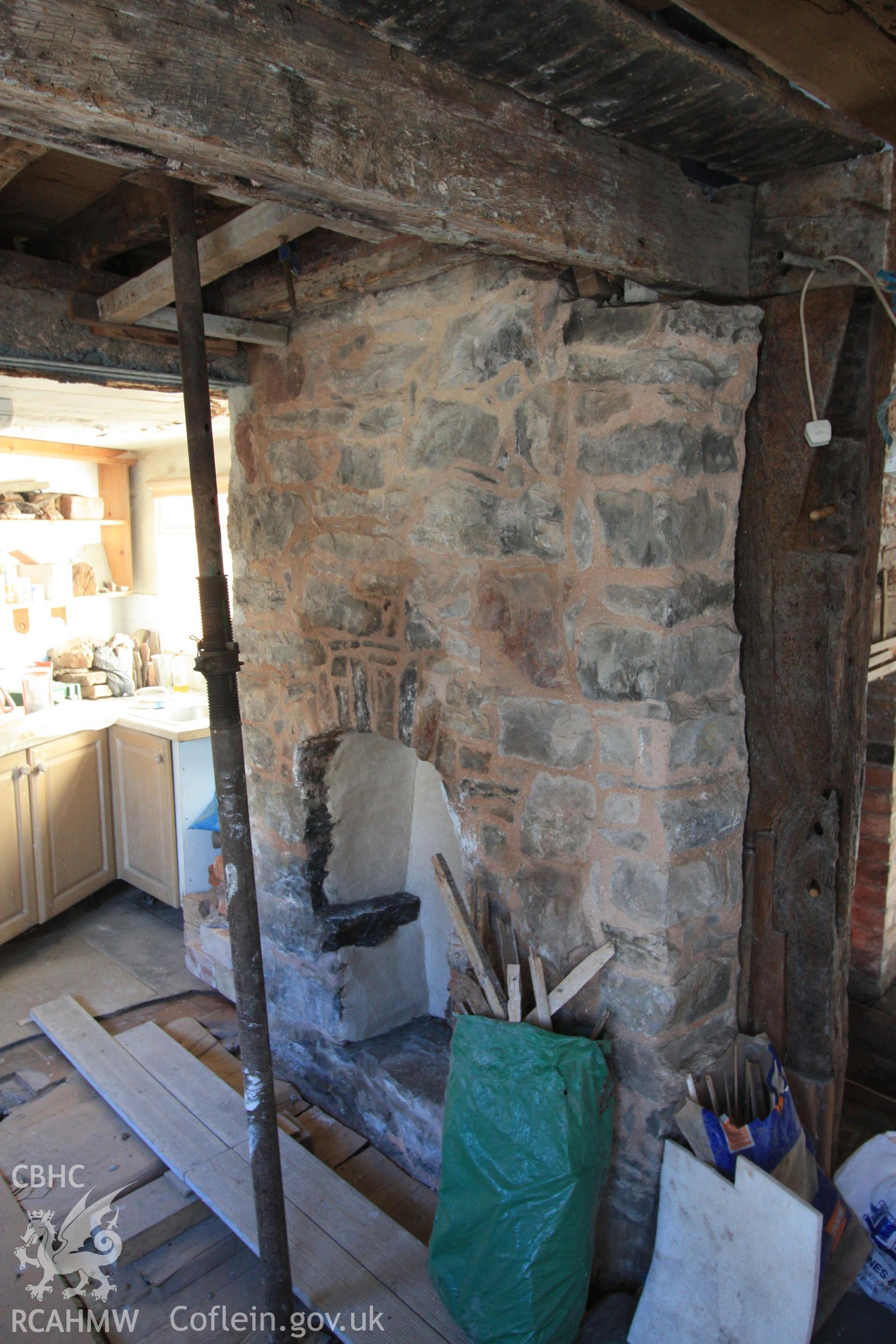Colour photograph showing stone fireplace to left of red brick. Also showing girt beam with mortices and peg holes for studs at Porth-y-Dwr, 67 Clwyd Street, Ruthin. Photographed during survey conducted by Geoff Ward on 10th June 2013.
