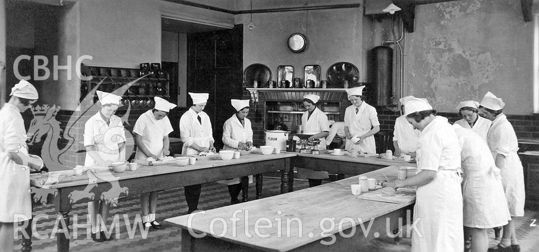 Digitised black and white photograph of a cookery class at Aberdare Girls Upper Comprehensive School, dated 1935. Included in material associated with a building recording conducted by Archaeology Wales, February 2018.