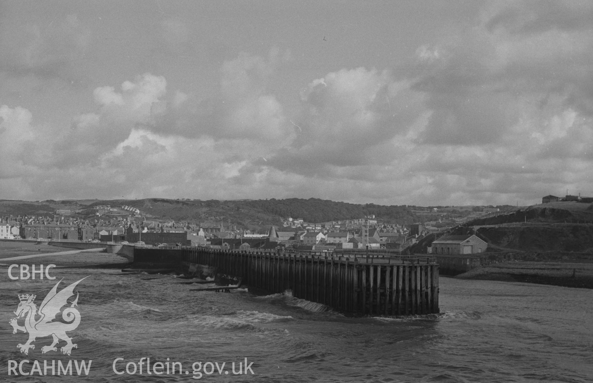 Digital copy of a black and white negative showing view of Aberystwyth jetty from the stone pier at Tanybwlch Beach. Photographed by Arthur O. Chater in September 1964 from Grid Reference SN 5781 8080, looking north east.