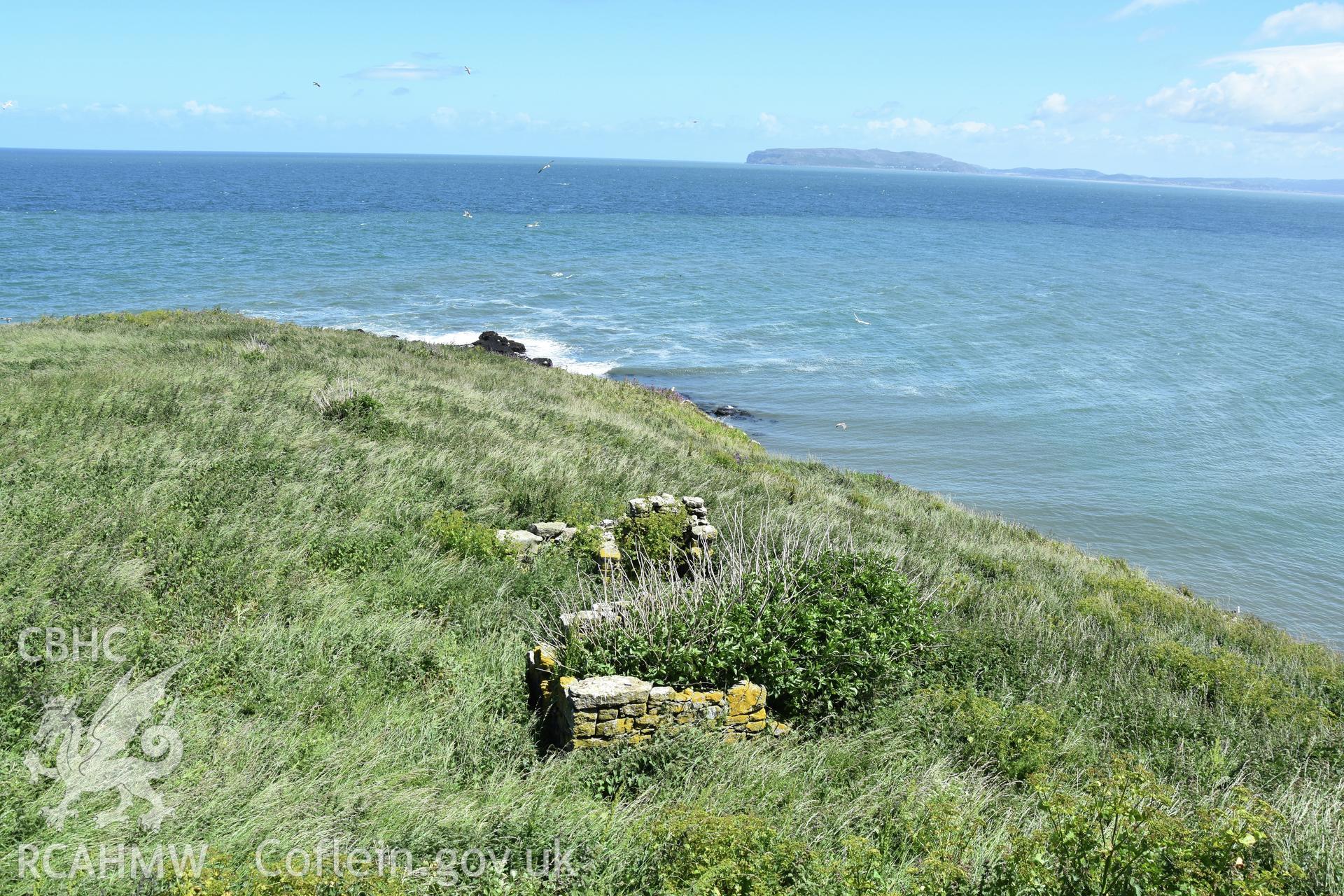 Investigator's photographic survey of the Telegraph Station on Puffin Island or Ynys Seiriol for the CHERISH Project. View of low stone structure set 10m away to the north-east of the main telegraph station. ? Crown: CHERISH PROJECT 2018. Produced with EU funds through the Ireland Wales Co-operation Programme 2014-2020. All material made freely available through the Open Government Licence.