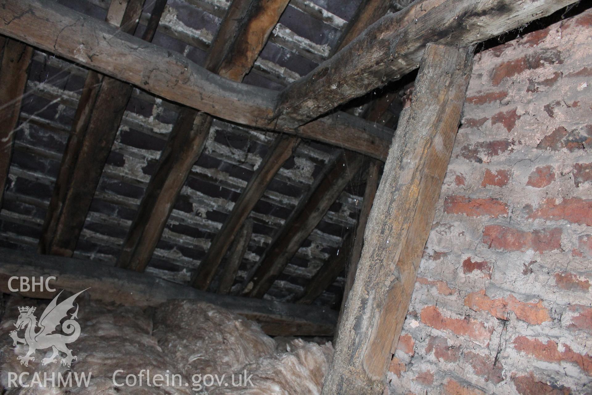 Colour photograph showing detail of red brick wall, insulating wool and timber roof frame at 5-7 Mwrog Street, Ruthin. Photographed during survey conducted by Geoff Ward on 14th May 2014.