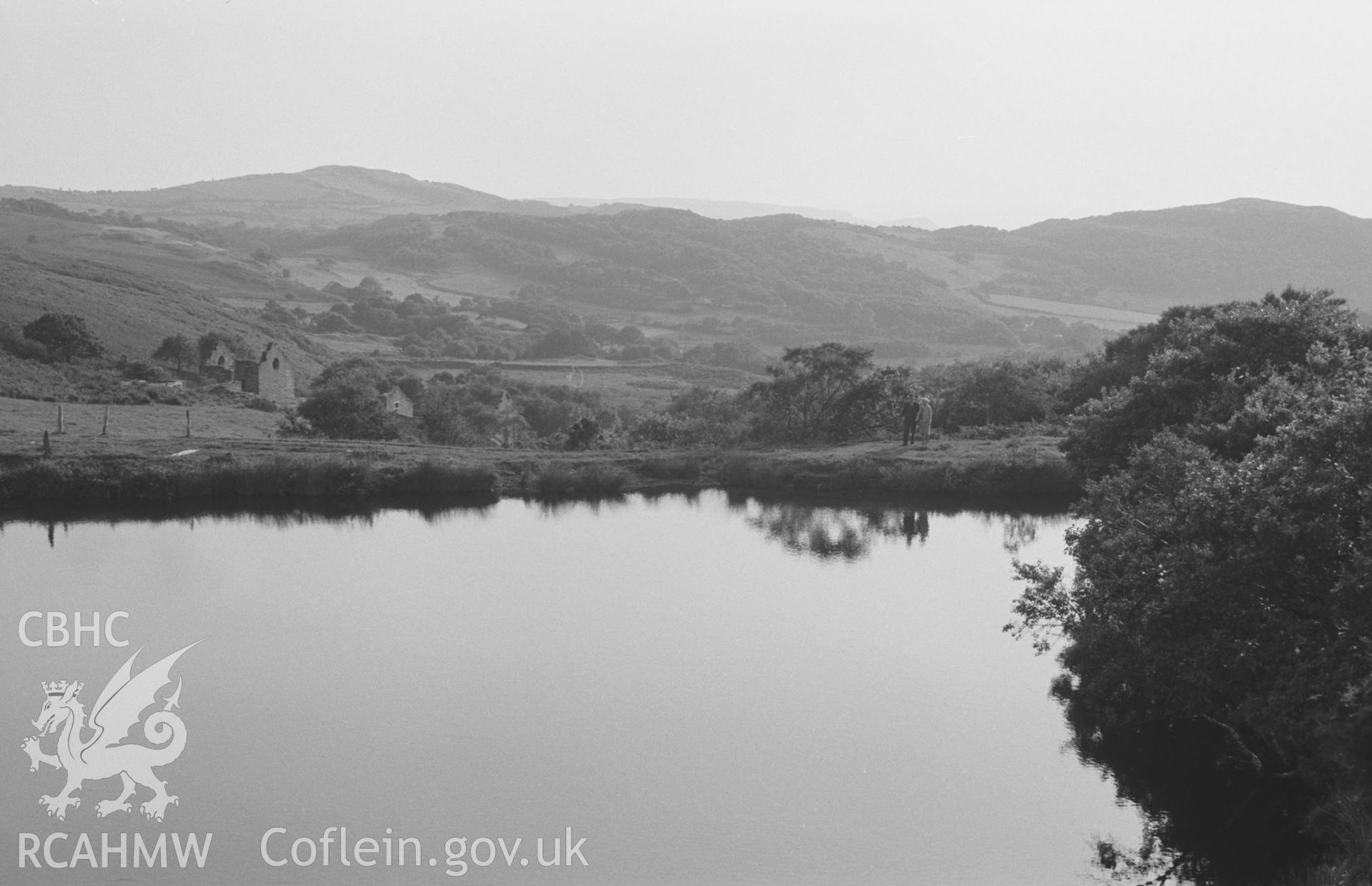 Digital copy of a black and white negative showing view across the middle reservoir to the mine buildings at Bryndyfi Mine, Eglwysfach, Machynlleth. Photographed by Arthur O. Chater in August 1966 looking south south west from Grid Reference SN 684 936.