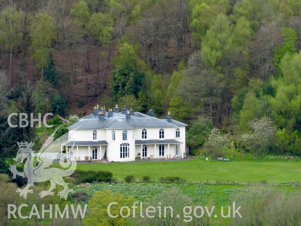 Colour photo of Dol-llys, Llanidloes, showing a distant view with the lawn and Pen yr Allt Wood behind taken by Mal Shears during April 2017.
