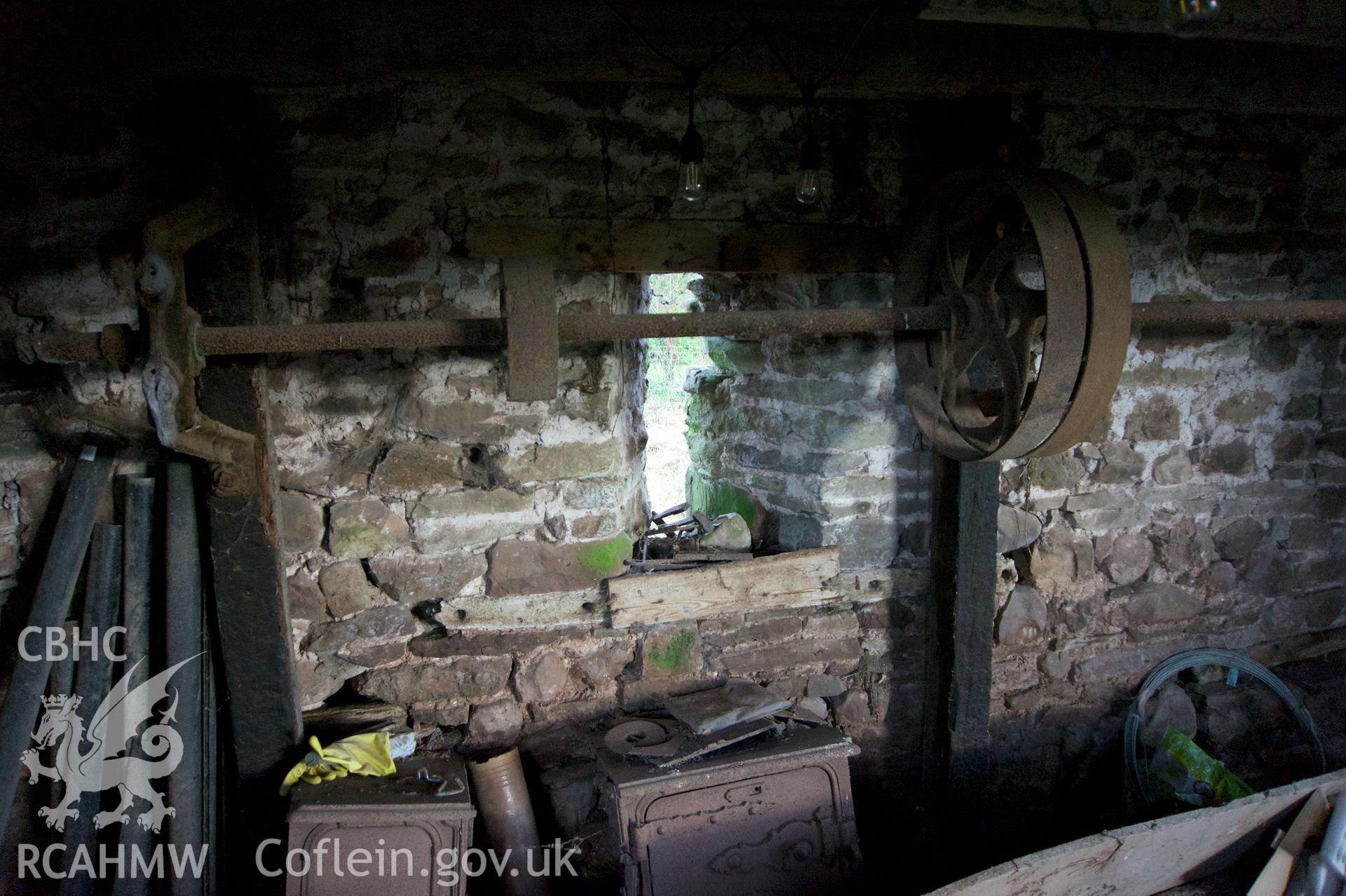 Inside of east gable wall below mezzanine showing slit window reveal & historic machinery at  Threshing Barn. Photographed for Historic Building Photographic Record of Middle Ton Threshing Barn, Llanvapley, by Dan Courtney of Cog Architects, 2019.