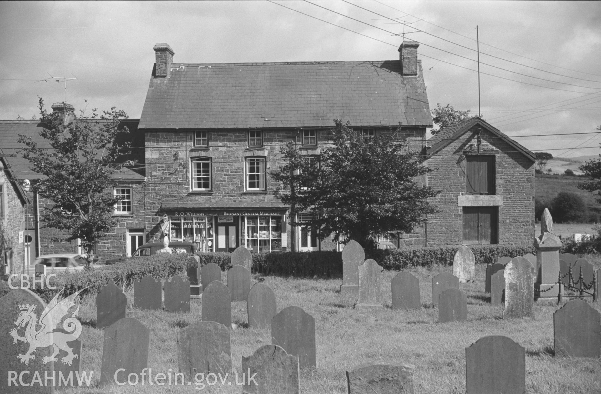 Digital copy of a black and white negative showing Bronant village shop, Lledrod, from the chapel graveyard. Warehouse with pulley on the right. Photographed by Arthur O. Chater on 2nd September 1966 looking east from Grid Reference SN 641 677.