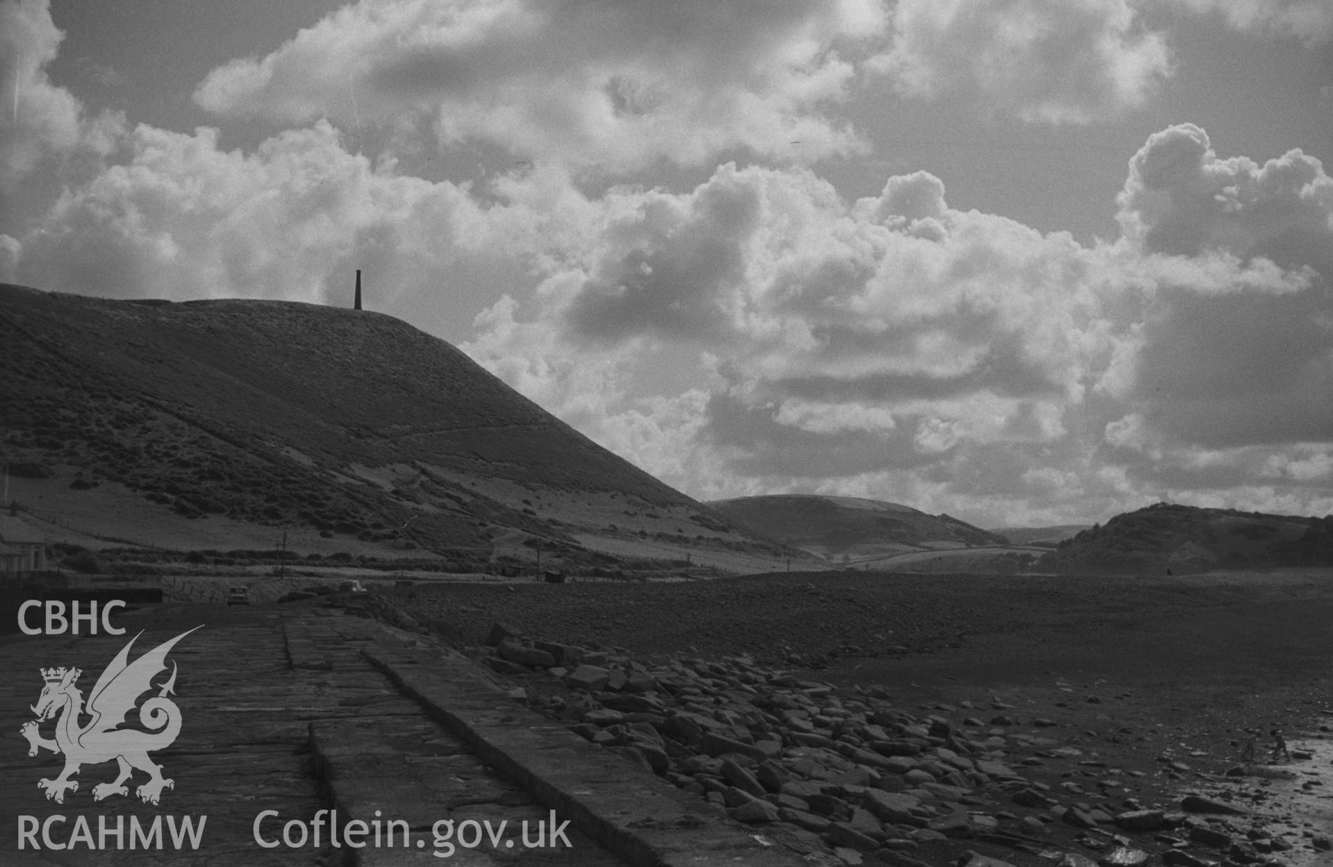Digital copy of a black and white negative showing view of Pen Dinas and the Wellington Monument. Photographed by Arthur O. Chater in September 1964 from Tanybwlch pier, Aberystwyth. Grid Reference SN 5785 8078. (Panorama. Photograph 7 of 10).