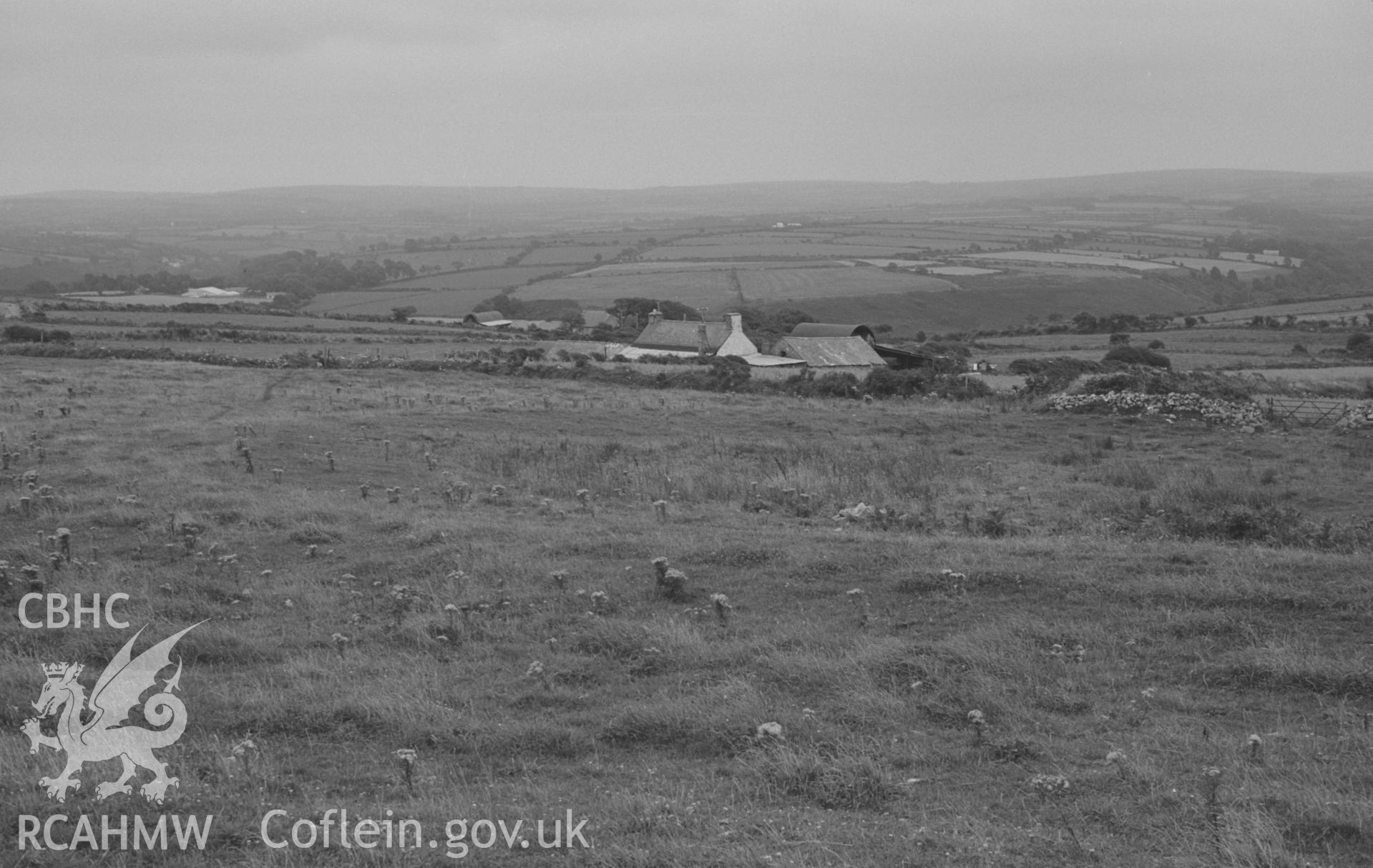 Digital copy of a black and white negative showing the circular, partly ploughed-out bank of Gaer-Wen pre-Roman Iron Age farmstead, 4km north east of Llangrannog. Gaer Wern Farm on he left, 575ft. Photographed by Arthur O. Chater in August 1967. (Looking south east from Grid Reference SN 345 564).