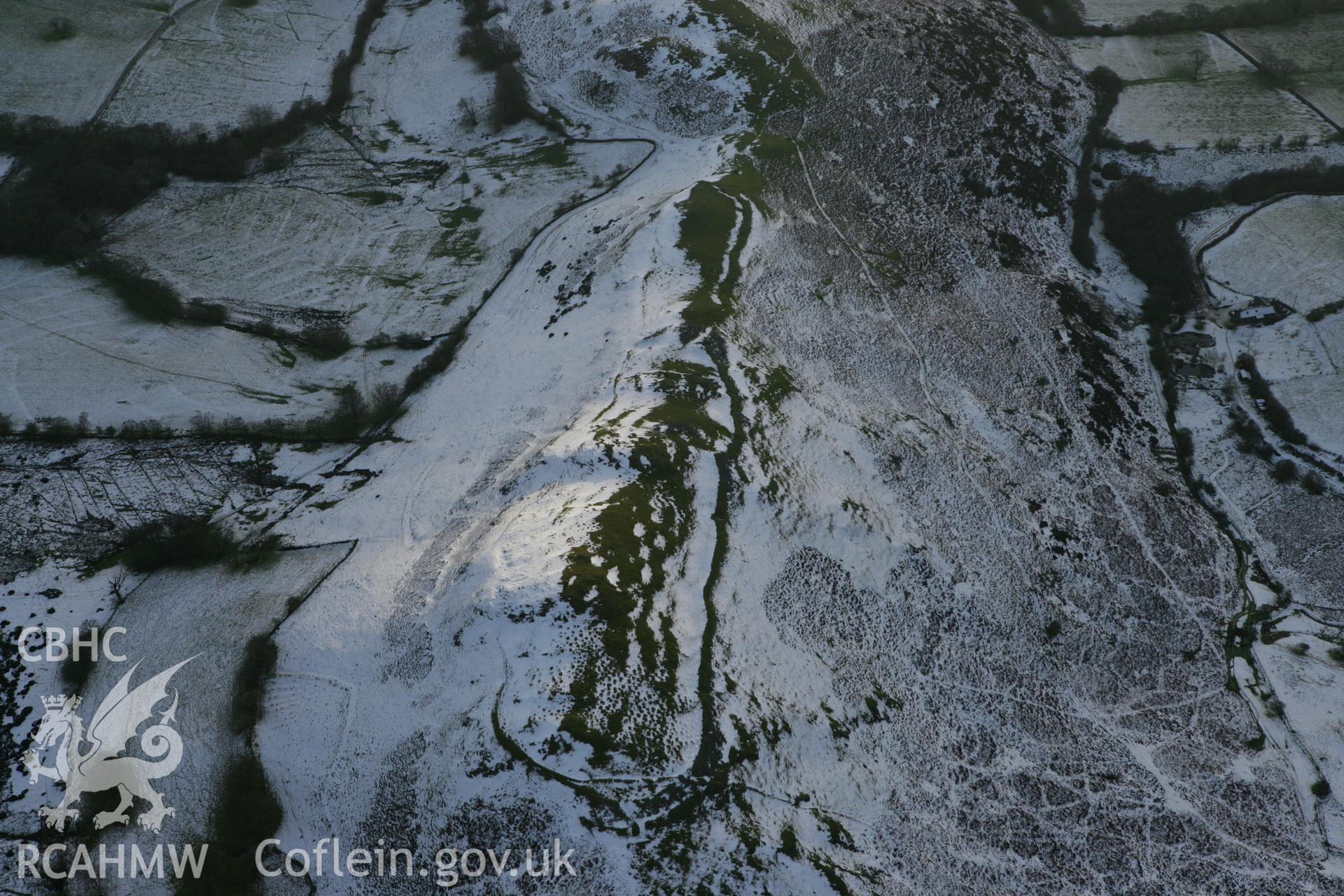 RCAHMW colour oblique photograph of Castle Bank hillfort, with melting snow highlighting defences and house platforms. Taken by Toby Driver on 18/12/2011.
