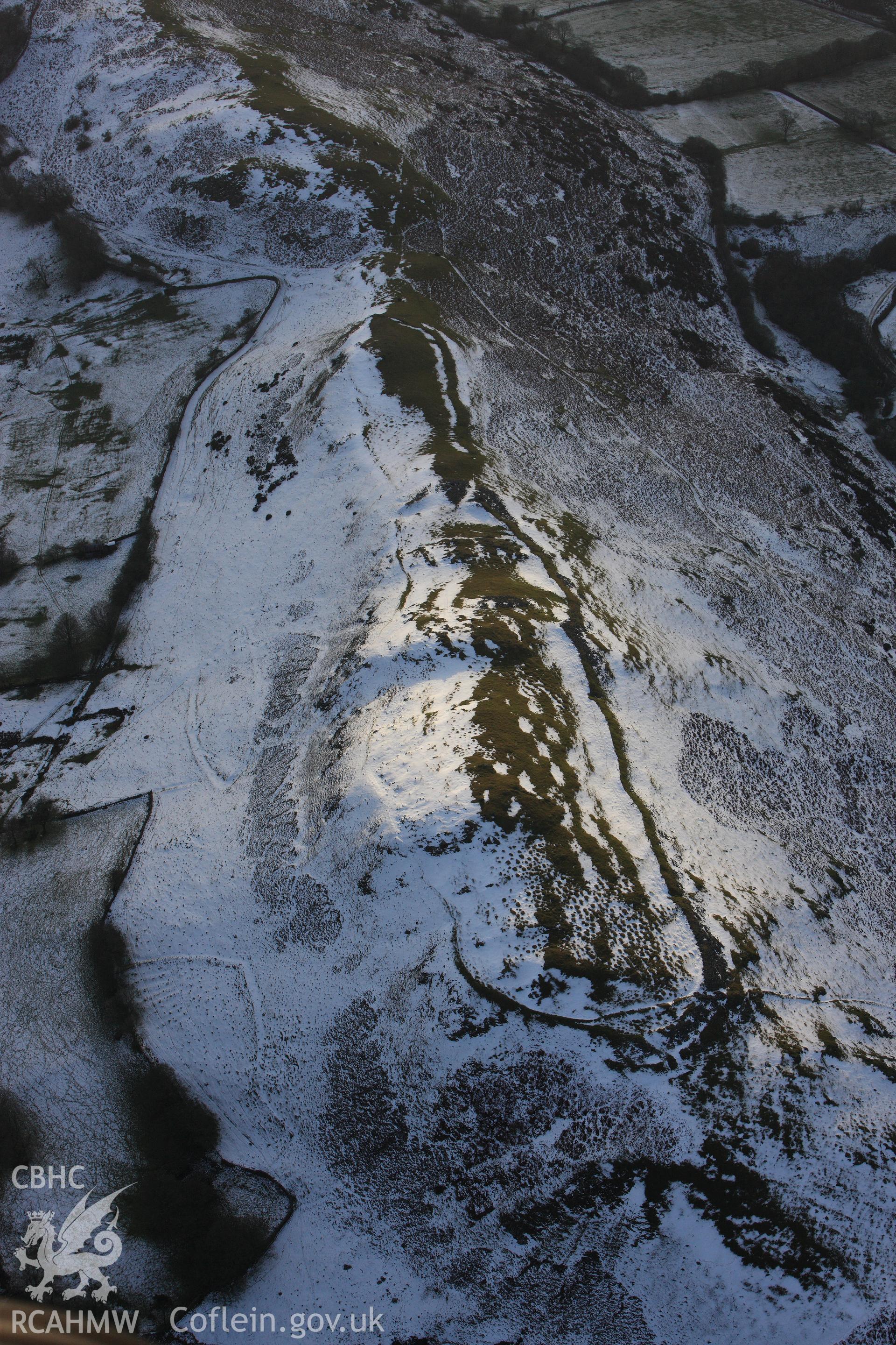 RCAHMW colour oblique photograph of Castle Bank hillfort, with melting snow highlighting defences and house platforms. Taken by Toby Driver on 18/12/2011.