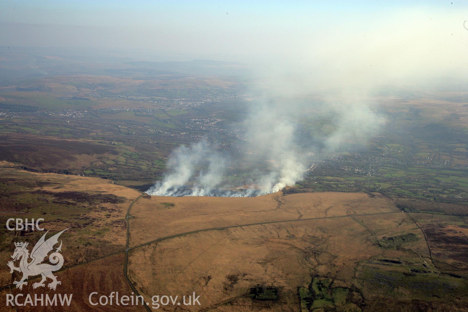 RCAHMW colour oblique photograph of Banc Crucorfod round cairn, with grass fire, view south towards Glanaman. Taken by Toby Driver and Oliver Davies on 28/03/2012.