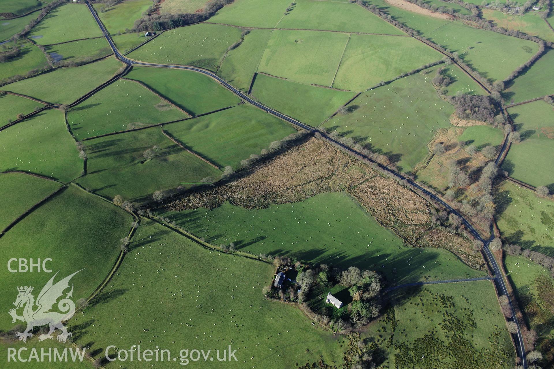 RCAHMW colour oblique photograph of Llanlleonfel Church, wide view showing earthworks (NPRN 421624). Taken by Toby Driver on 23/11/2012.