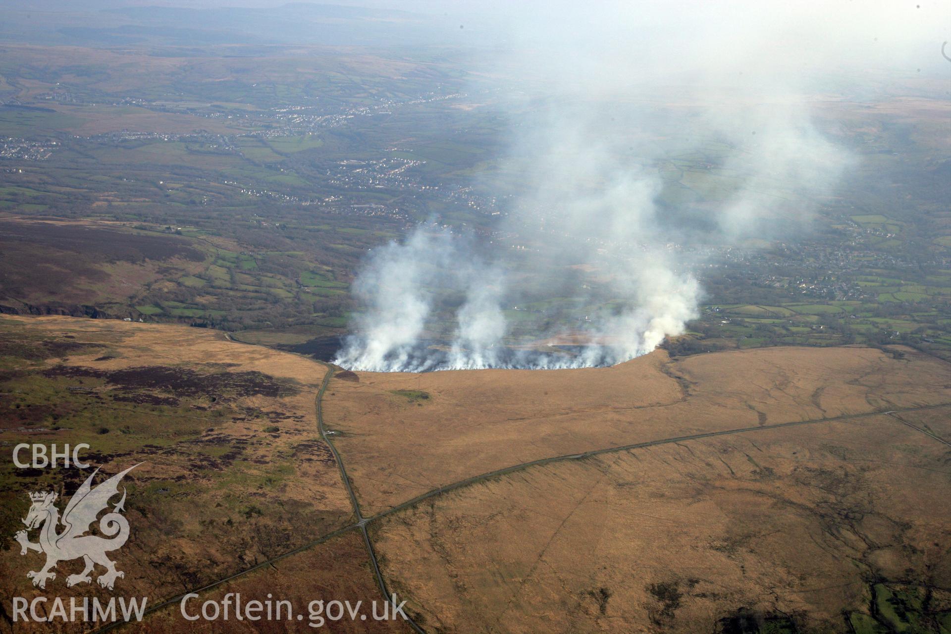 RCAHMW colour oblique photograph of Banc Crucorfod round cairn, with grass fire, view south towards Glanaman. Taken by Toby Driver and Oliver Davies on 28/03/2012.