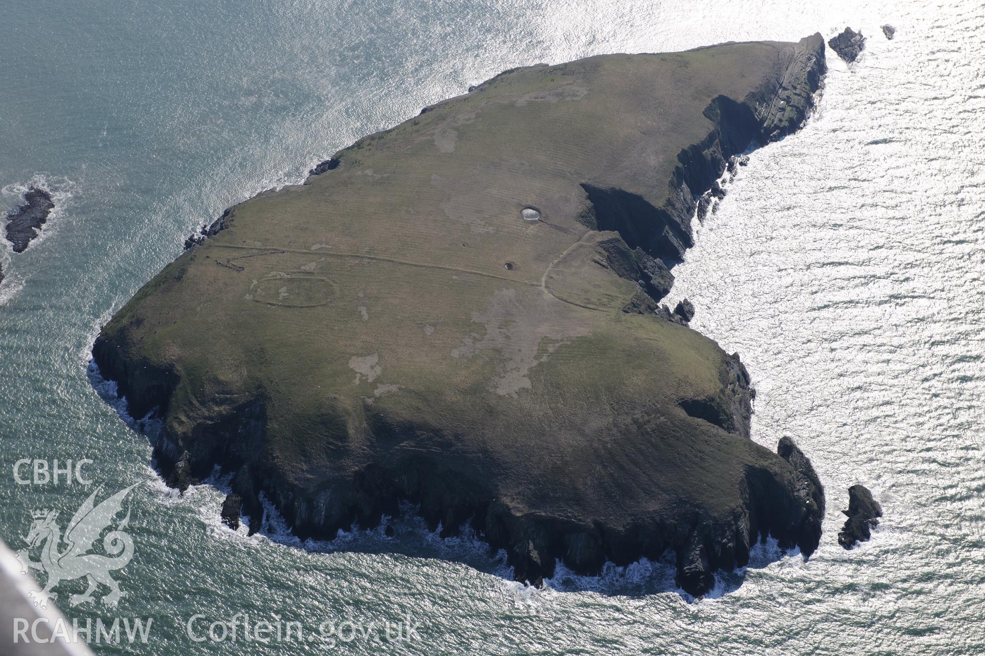 Cardigan Island, viewed from the north west. Features visible include cultivation features; landing point; linear bank crossing; ponds; possible cairn; possible round house; promontory enclosure and settlement enclosure. Oblique aerial photograph taken during the Royal Commission's programme of archaeological aerial reconnaissance by Toby Driver on 2nd April 2013.