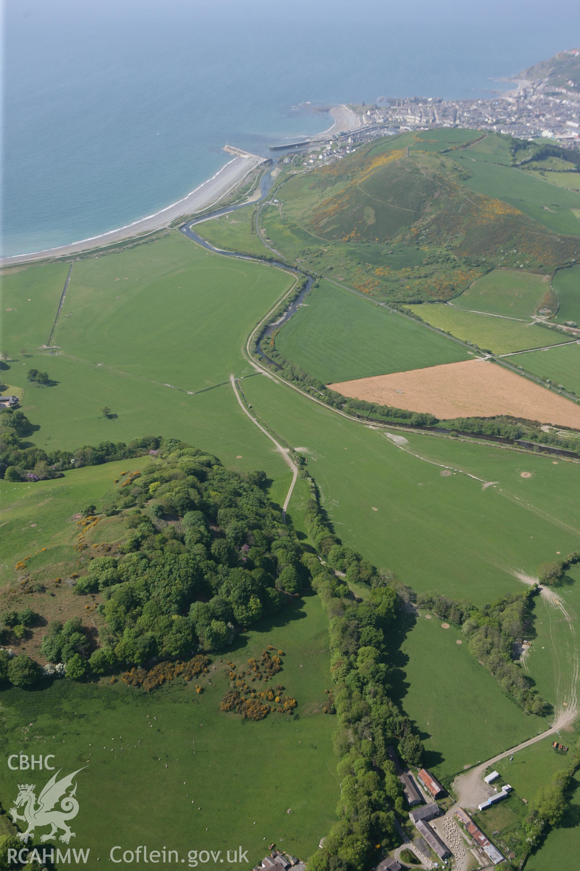RCAHMW colour oblique photograph of Tanycastell motte, wide landscape view. Taken by Toby Driver on 25/05/2010.