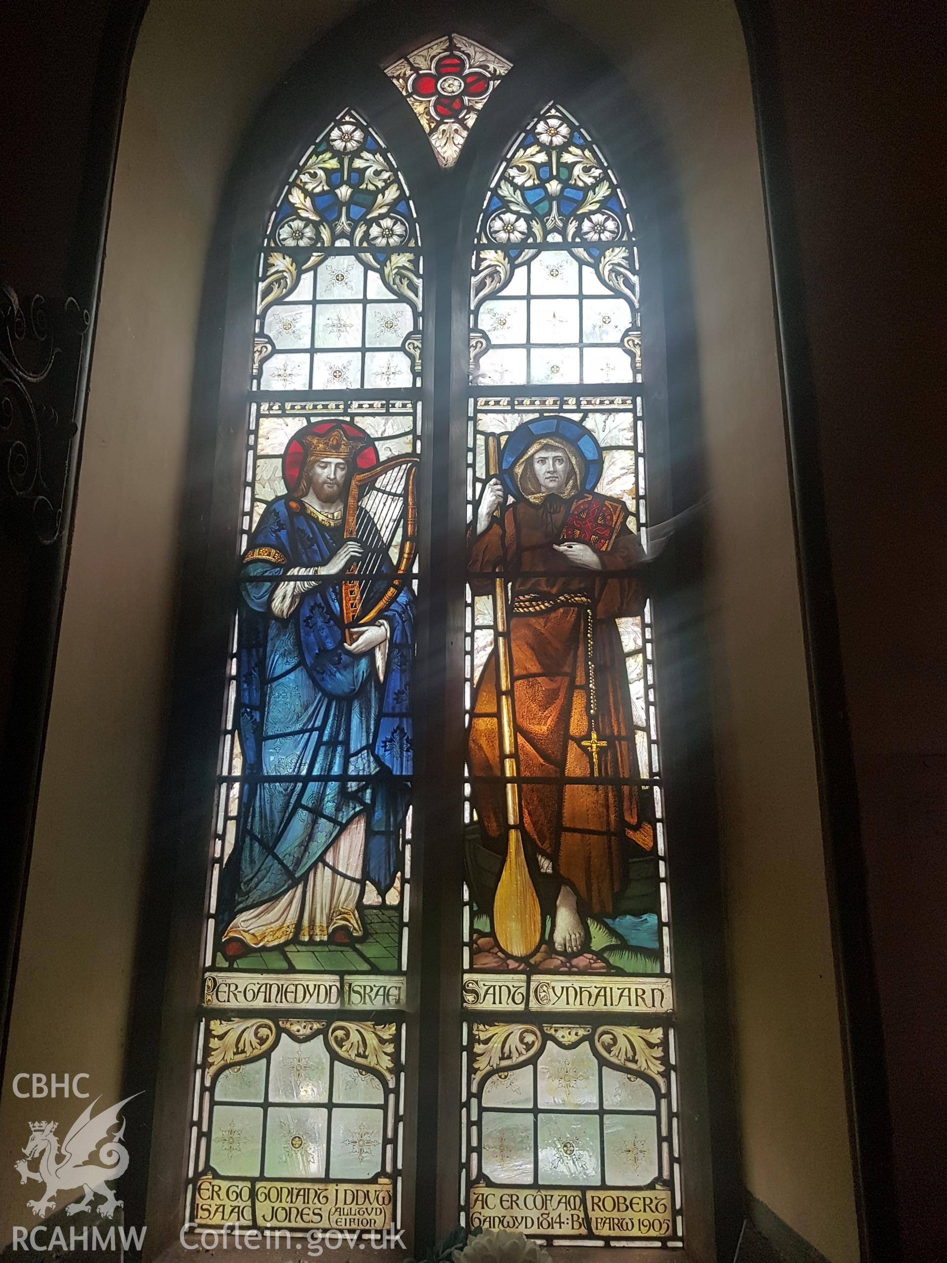 Stained glass windows, one showing St Cynhaiarn. Photographed by Helen Rowe of RCAHMW on 10th October 2020.