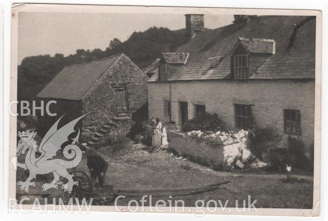 Digitised copy of a photograph depicting the farmhouse and the cowshed at Cwm, Llandderfel. The figures are Richard and Catherine Davies. Original photograph dated between 1923 (when Richard Davies took over the tenancy from John Jones, his father in law) and 1945 (the gable-end of the cowshed was plastered by a German prisoner of war that year). Donated by Meirion Davies in 2020.