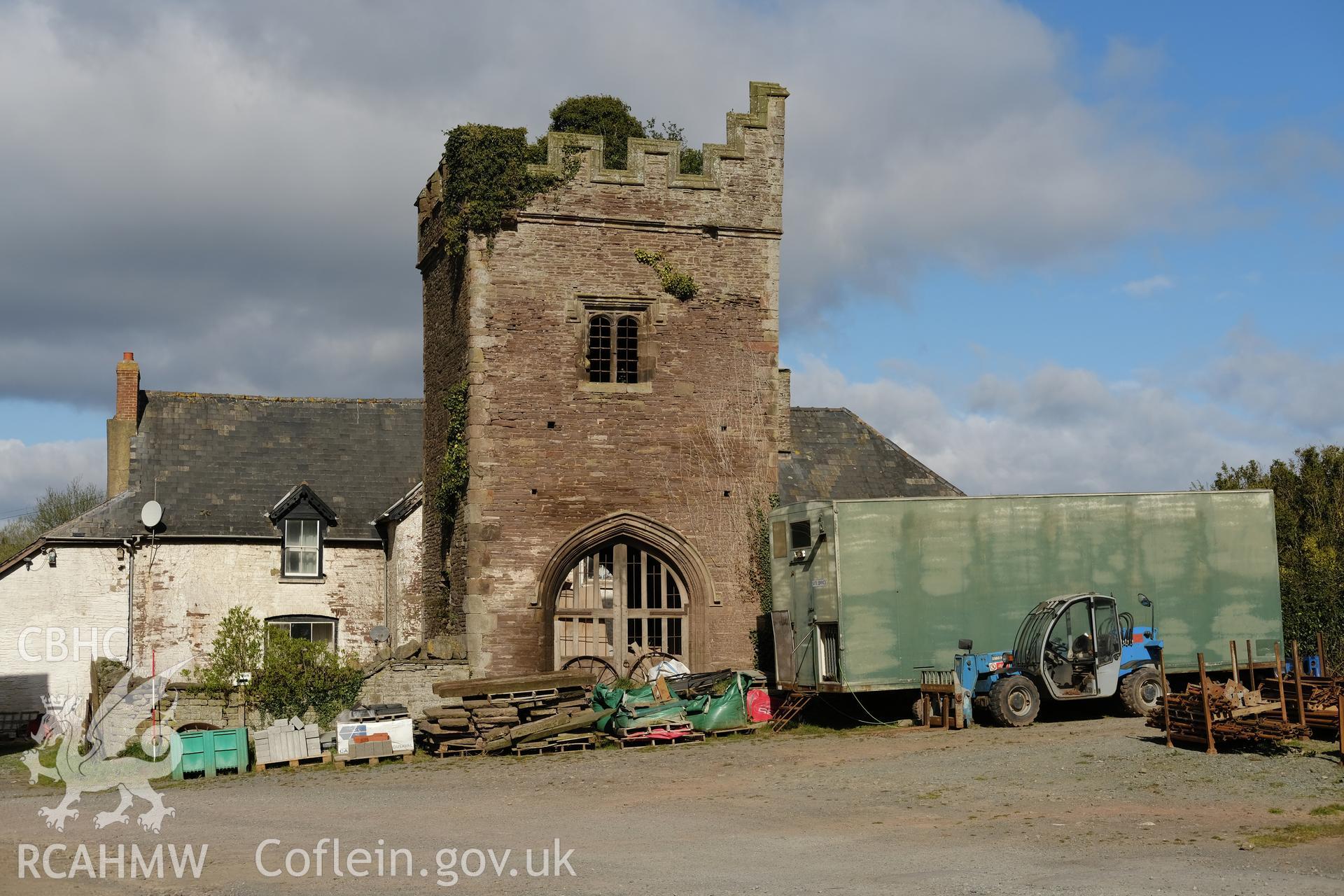 Colour photograph showing Great Porthmel Gatehouse in farmyard with farmhouse behind, looking NW. Produced as part of Historic Building Recording for Great Porthamel Gatehouse, carried out by Richard Hayman, April 2021.