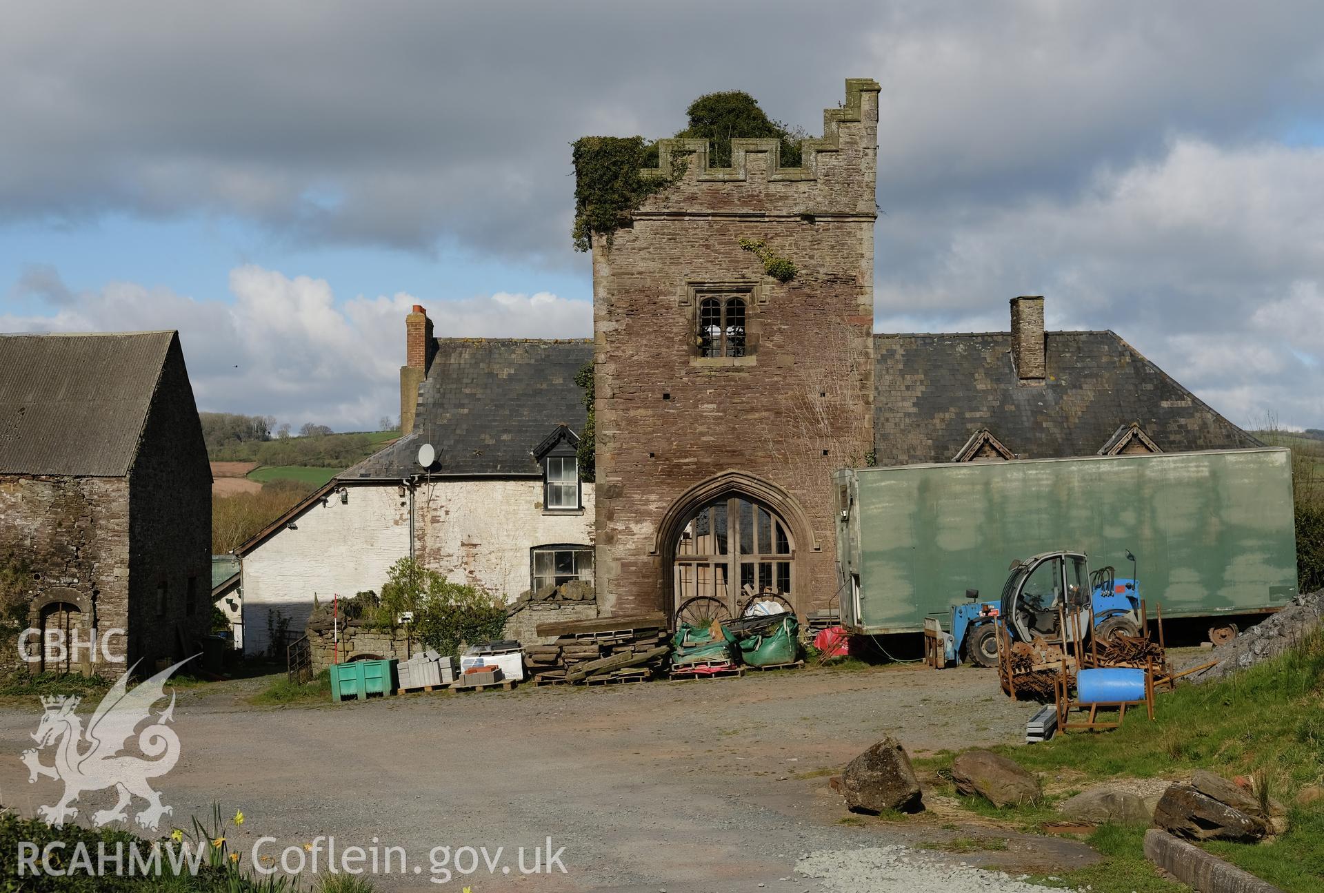 Colour photograph showing Great Porthmel Gatehouse in farmyard with farmhouse behind, looking W. Produced as part of Historic Building Recording for Great Porthamel Gatehouse, carried out by Richard Hayman, April 2021.