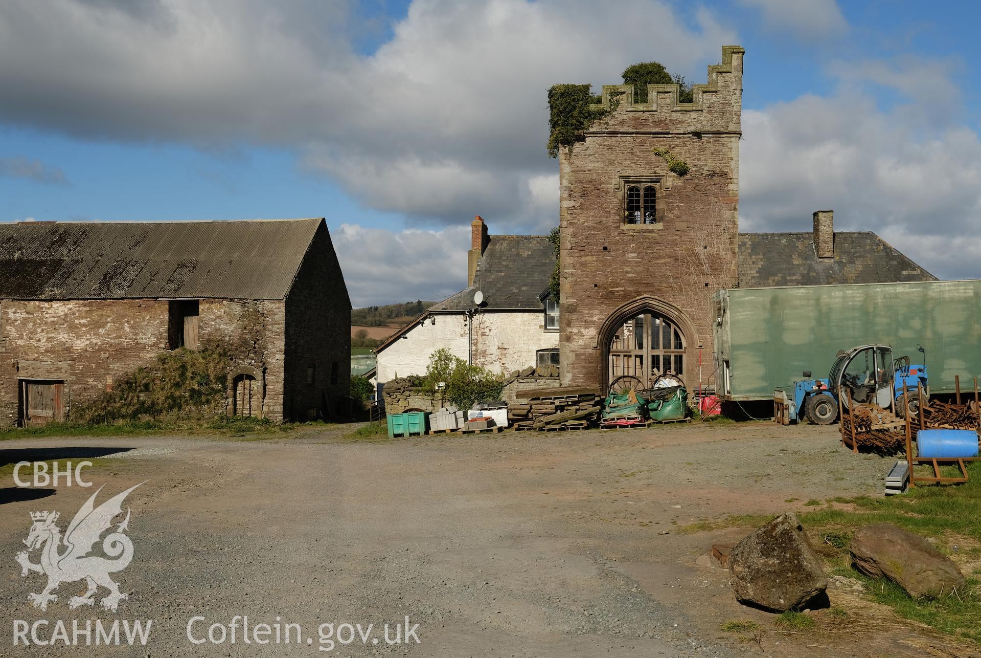 Colour photograph showing Great Porthmel Gatehouse in farmyard with farmhouse and farm building, looking W. Produced as part of Historic Building Recording for Great Porthamel Gatehouse, carried out by Richard Hayman, April 2021.