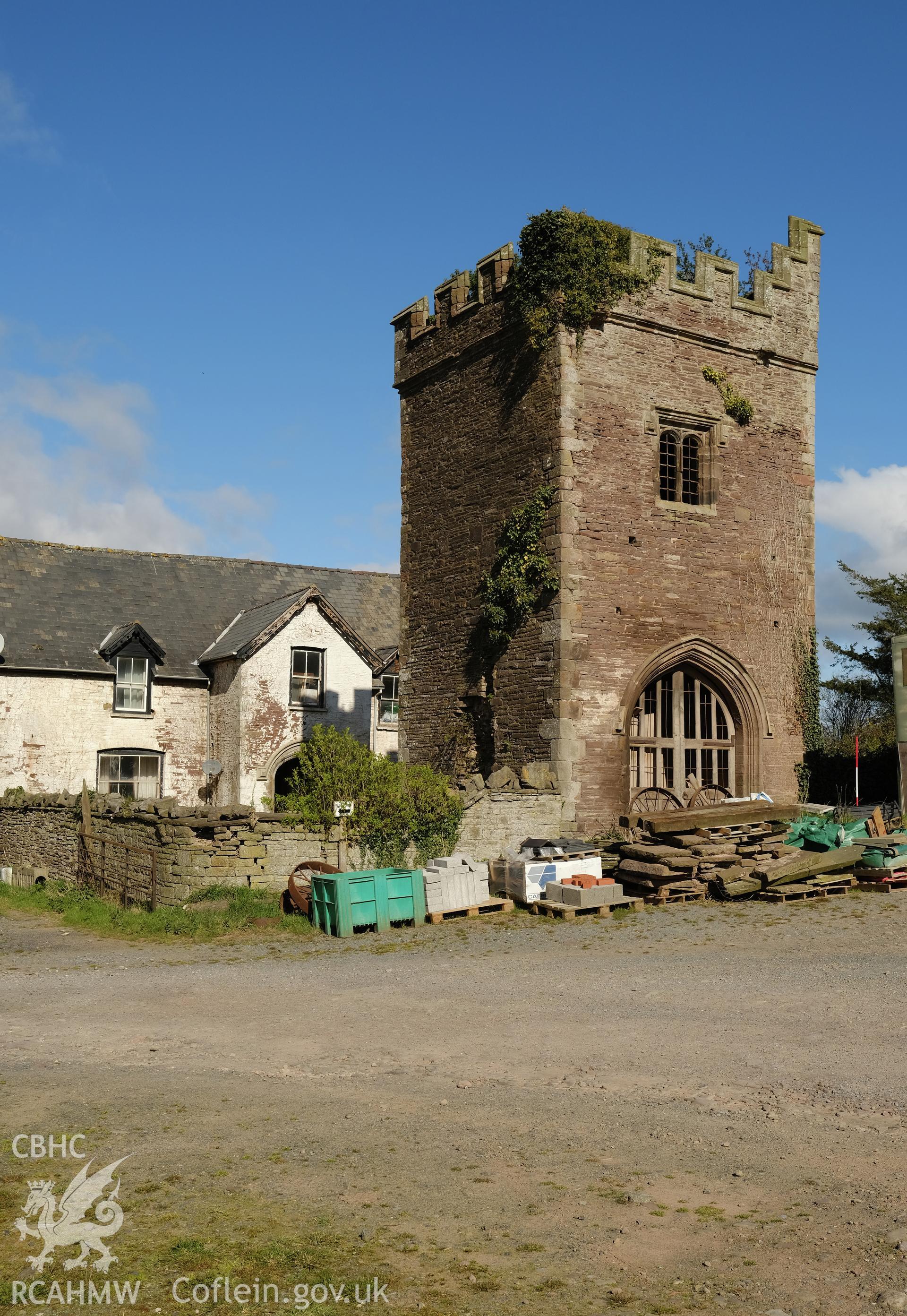 Colour photograph showing Great Porthmel Gatehouse in farmyard with farmhouse and garden wall, looking NW. Produced as part of Historic Building Recording for Great Porthamel Gatehouse, carried out by Richard Hayman, April 2021.