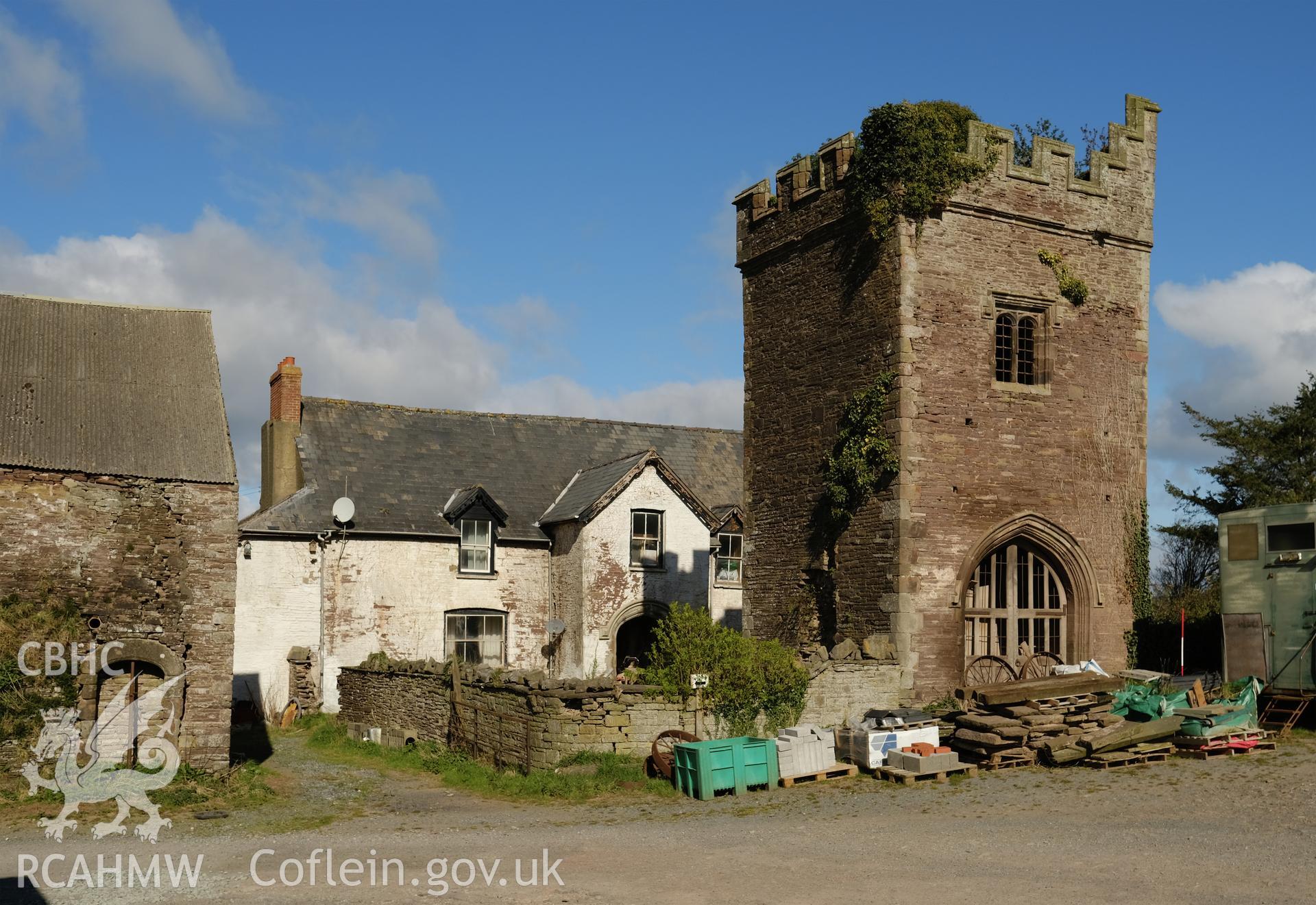 Colour photograph showing Great Porthmel Gatehouse in farmyard with farmhouse and garden wall, looking NW. Produced as part of Historic Building Recording for Great Porthamel Gatehouse, carried out by Richard Hayman, April 2021.