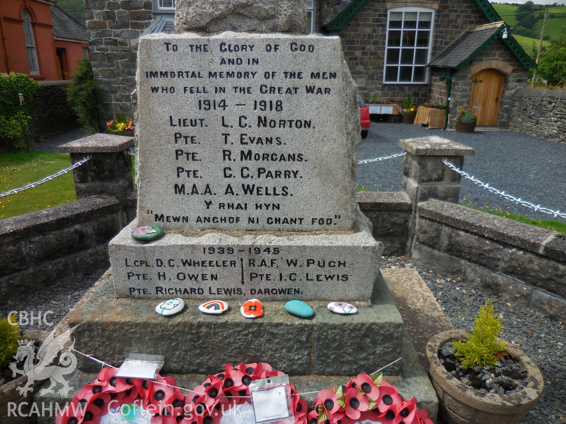 Colour digital photograph showing names on Cemmaes war memorial, painted stones and poppy wreaths, taken in November 2021.