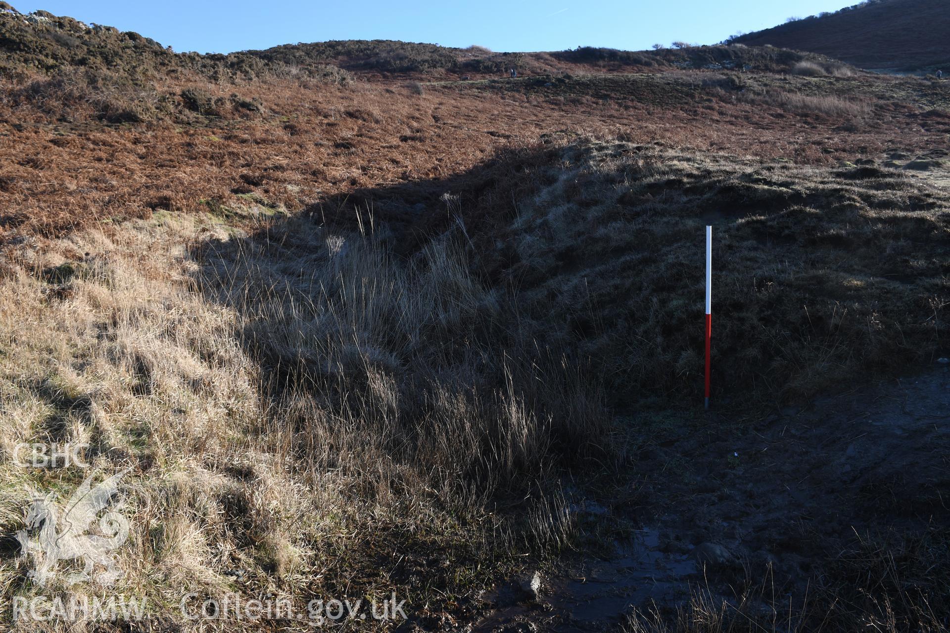 N end of outer rampart and ditch. 1m scale. Camera facing SE. Photographic survey of Castell Bach promontory fort (NPRN 93914) using 1m scales and human figures. Undertaken by Hannah Genders Boyd for CHERISH project condition monitoring 13/01/2022.
Produced with EU funds through the Ireland Wales Co-operation Programme 2014-2020. All material made freely available through the Open Government Licence.