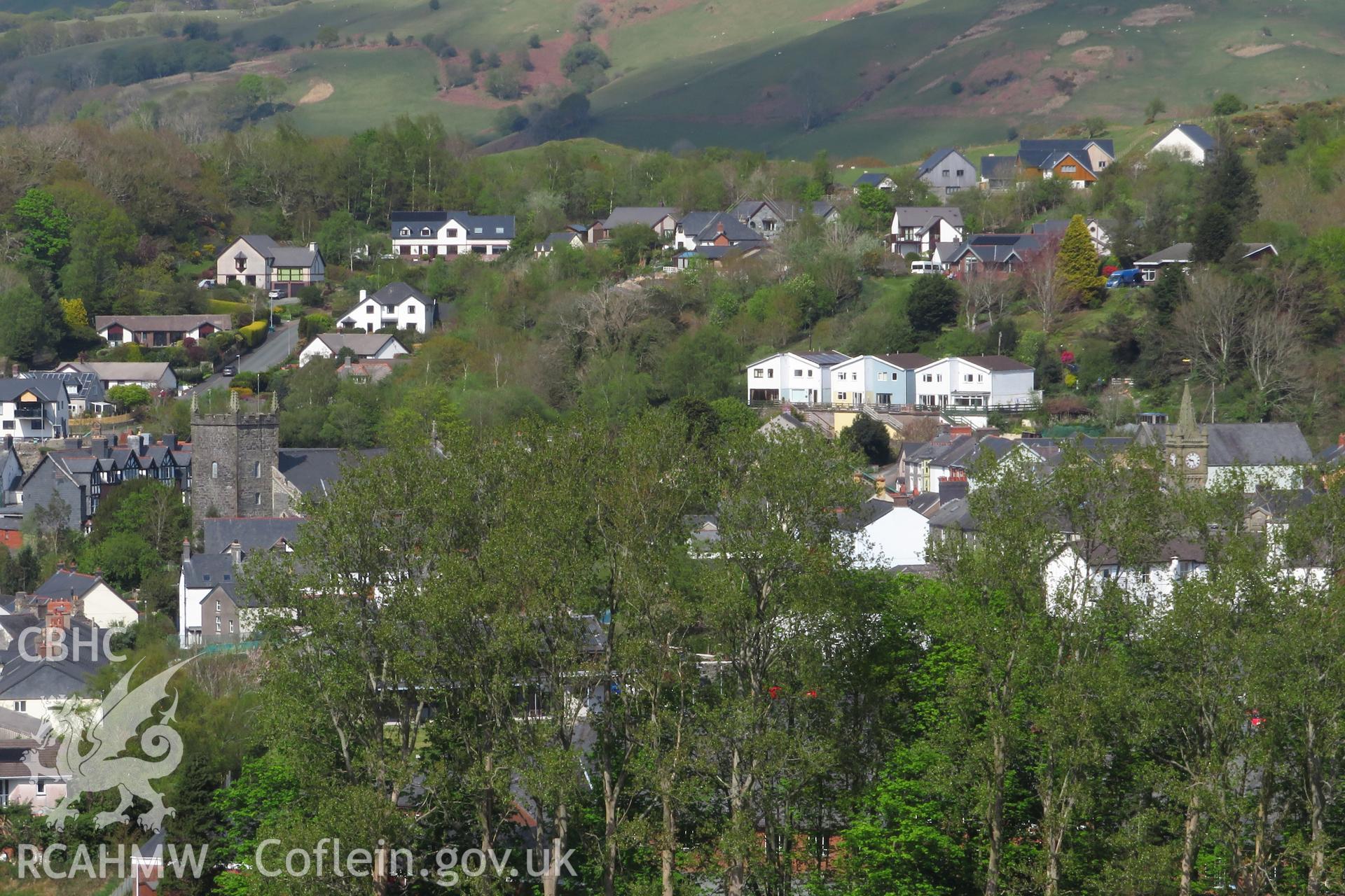 View of 1-6 Penrallt Estate, Machynlleth, from the south west, showing St Peter's Church, the clock tower, and Mynydd Griffiths, taken from Cae-Gybi Footpath on 27 April 2022.