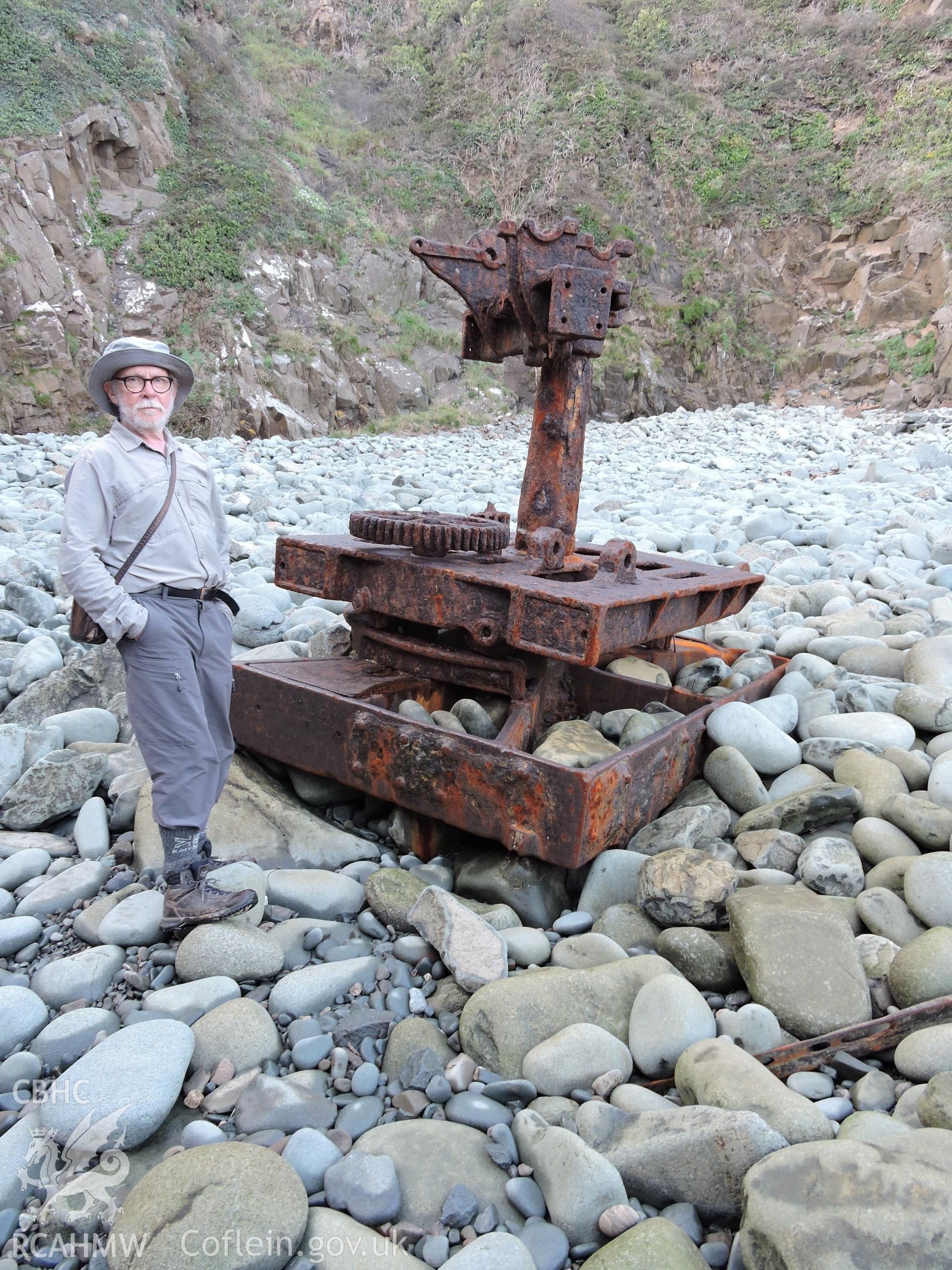 Colour photograph showing old piece of machinery at the quay, with human for scale. Part of a digital photographic survey of Porth y Pistyll, Aberdaron, produced in 2020 by Michael Statham.