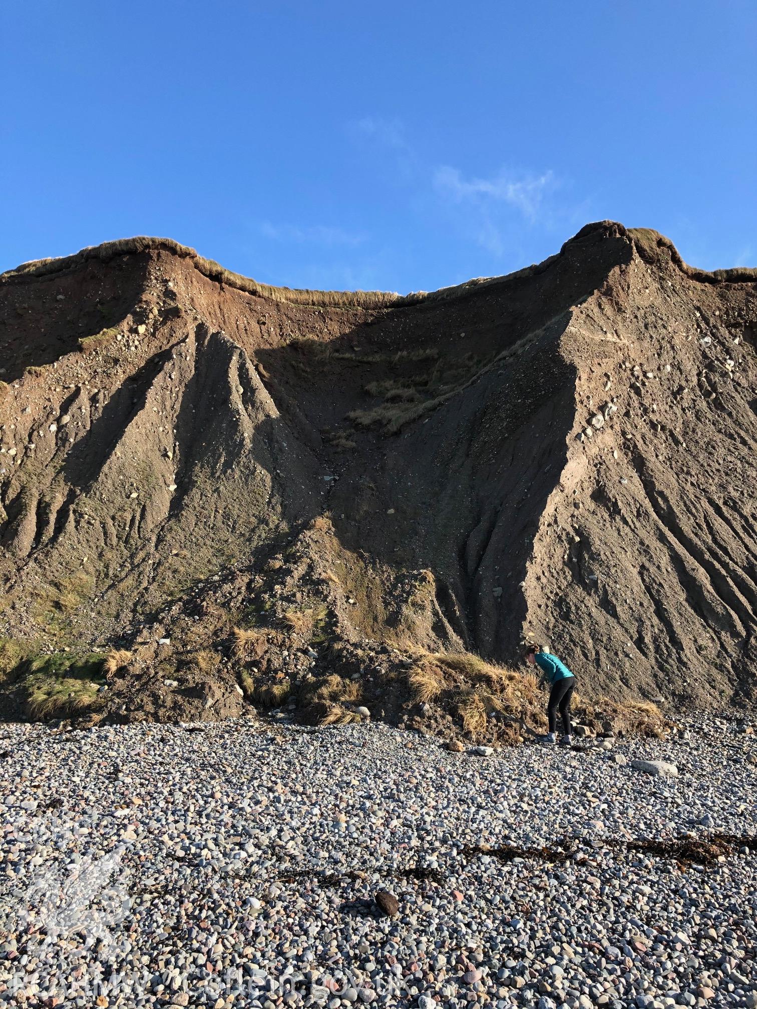 Shot of beach and eroding edge, figure for scale. Taken by Toby Driver. Produced with EU funds through the Ireland Wales Co-operation Programme 2014-2023. All material made freely available through the Open Government Licence.