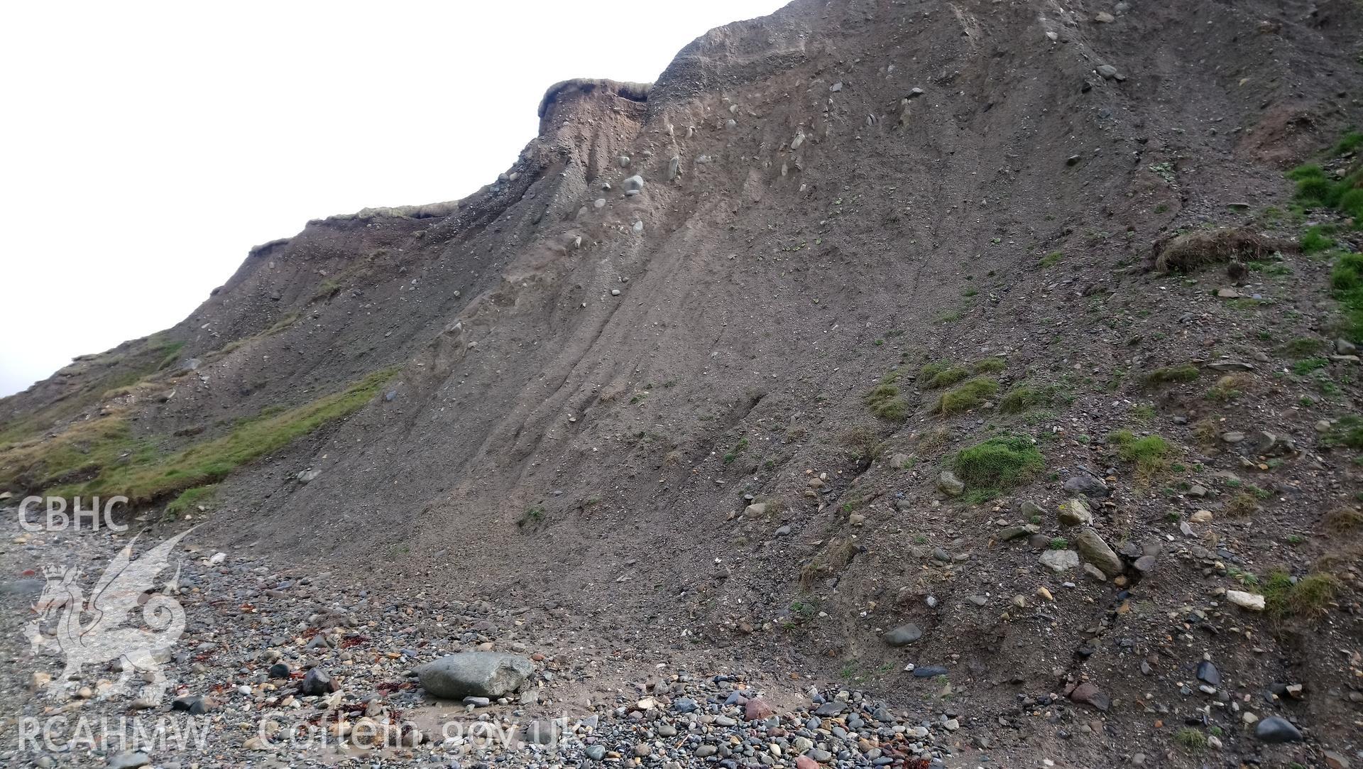 Eroding cliff face with stratigraphic layers visible. Camera facing NE. Taken by Toby Driver. Produced with EU funds through the Ireland Wales Co-operation Programme 2014-2023. All material made freely available through the Open Government Licence.