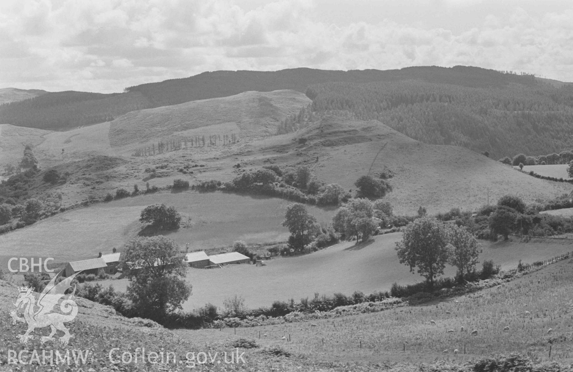 Digital copy of a black and white negative showing Pen-Grogwynion Farm and Castell Grogwynion iron age fort. Photographed by Arthur Chater on 17 August 1968. Looking south south west from Grid Reference SN 723 730.