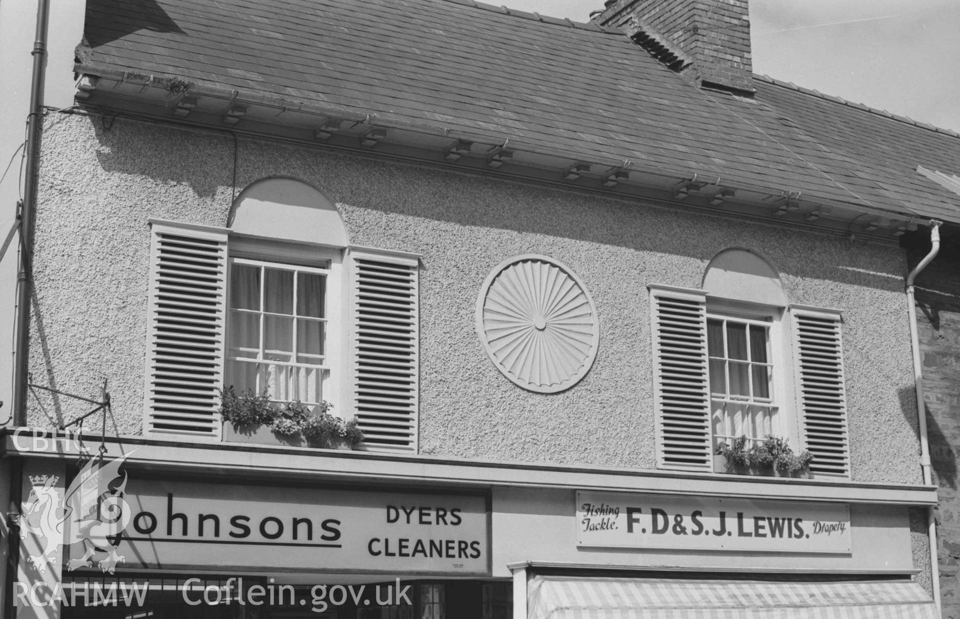 Digital copy of a black and white negative showing F. D. S. Lewis's fishing tackle shop and Johnsons Dryers Cleaners on the west side of Cardigan High Street. Photographed by Arthur Chater on 30 August 1968. Looking west from Grid Reference SN 178 463.