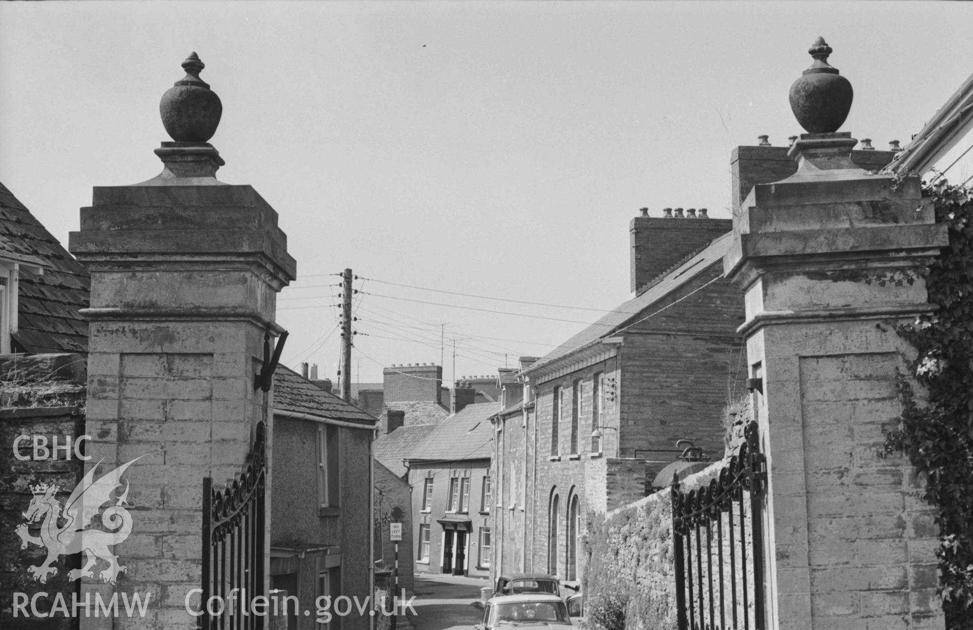 Digital copy of a black and white negative showing view looking out of the gateway at the south west corner of St Mary's Church yard, Cardigan. Photographed by Arthur Chater on 30 August 1968. Looking west from Grid Reference SN 1804 4602.