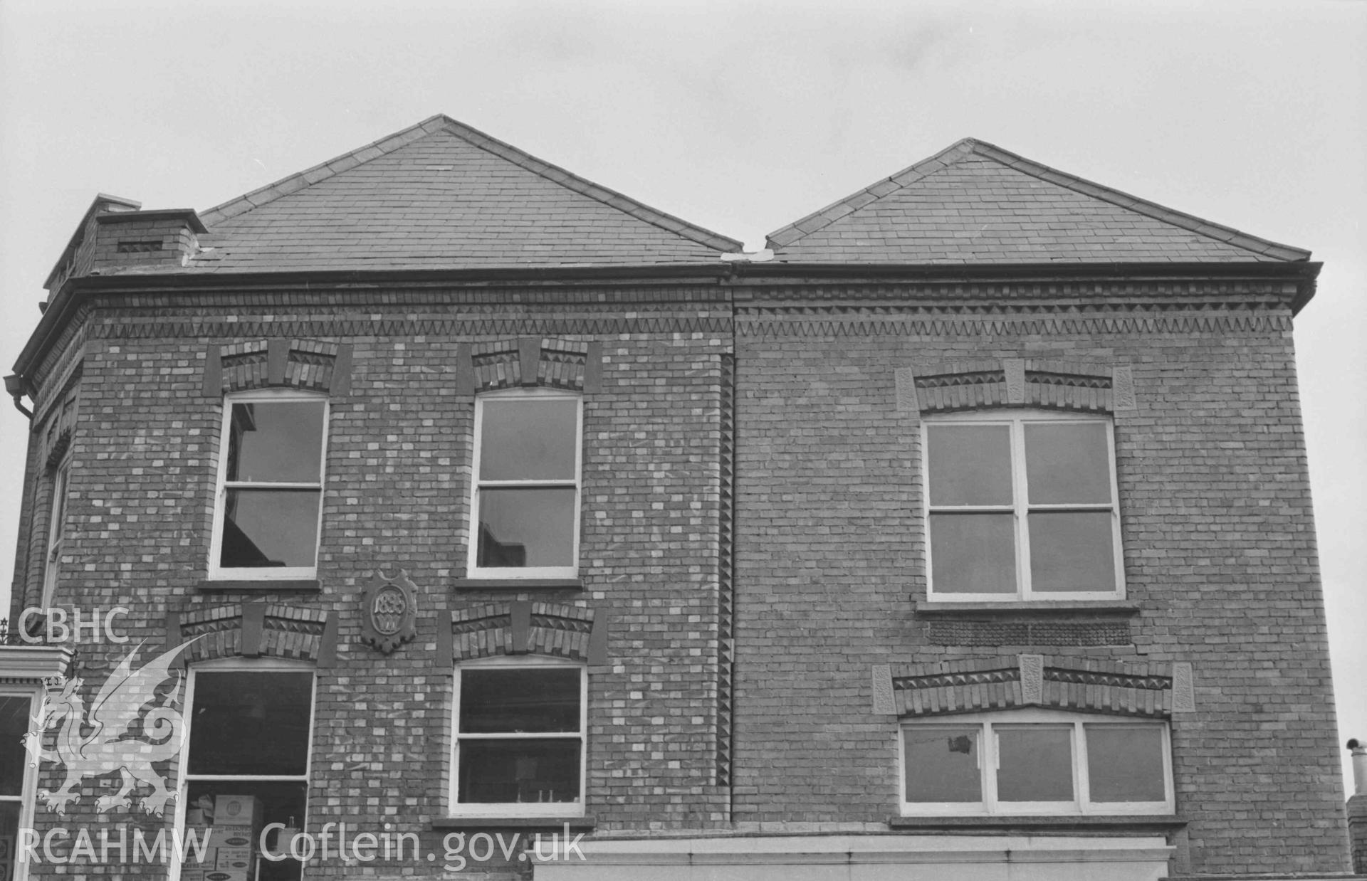 Digital copy of a black and white negative showing decorative tiling on upper stories of houses opposite the Guildhall, High Street, at the corner with Priory Street, Cardigan. Photographed by Arthur Chater on 30 August 1968. Looking east south east from Grid Reference SN 1778 4615.