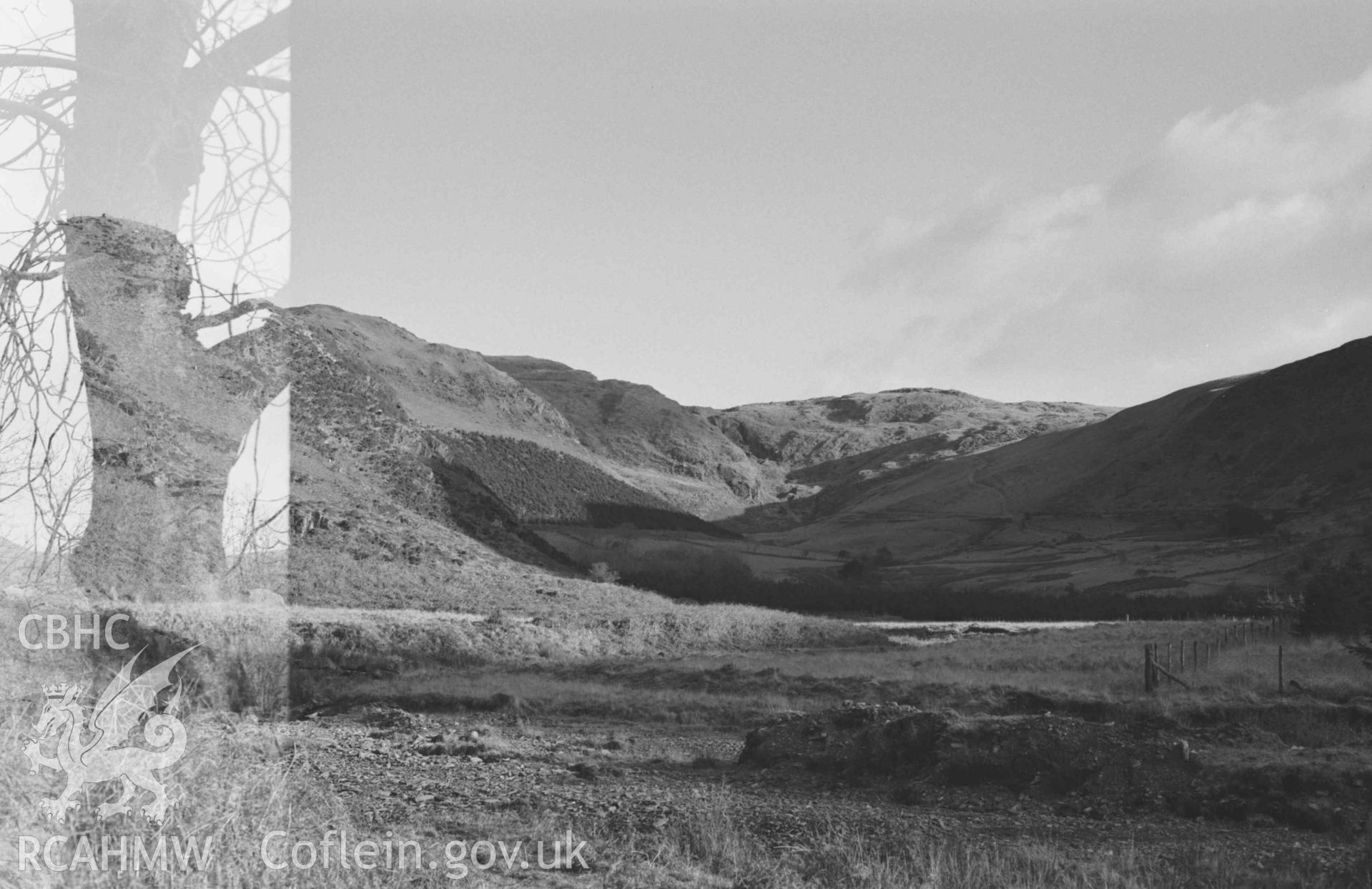 Digital copy of a black and white negative showing view to the Hafren mine at the head of the Nant y Maes-Mawr from the lane by the bridge 750m below Cyneiniog. Photographed by Arthur Chater on 26 December 1968. Looking east from Grid Reference SN 7120 8790.