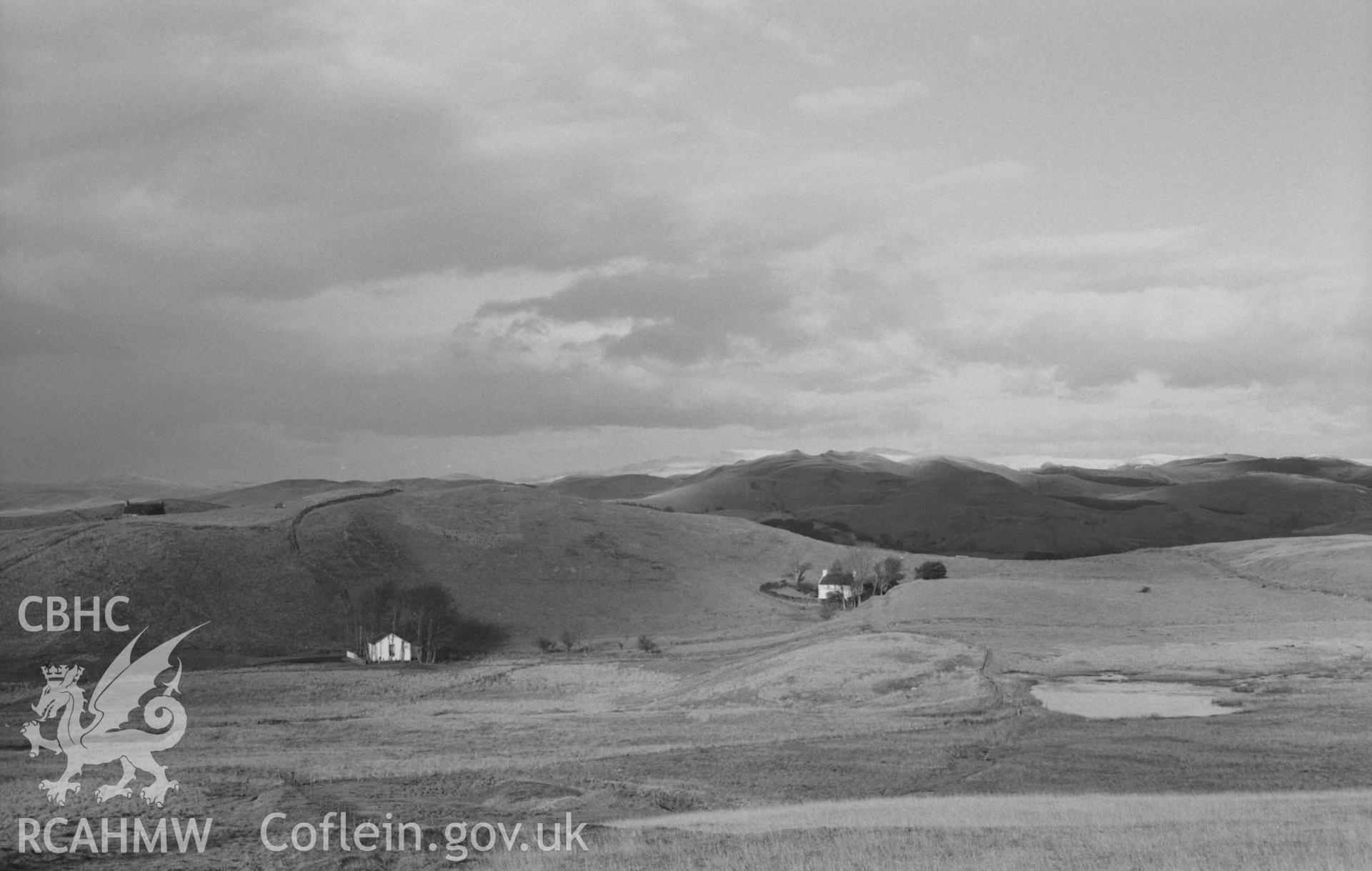Digital copy of a black and white negative showing Pen-Glog-Uchaf (roof only visible, top left), Methodist Chapel (lower left) and Pont-y-Ffynnon from the track on the north side of Glog-Fawr mine. Photographed by Arthur Chater on 27 December 1968. Looking north from Grid Reference SN 7500 7110.