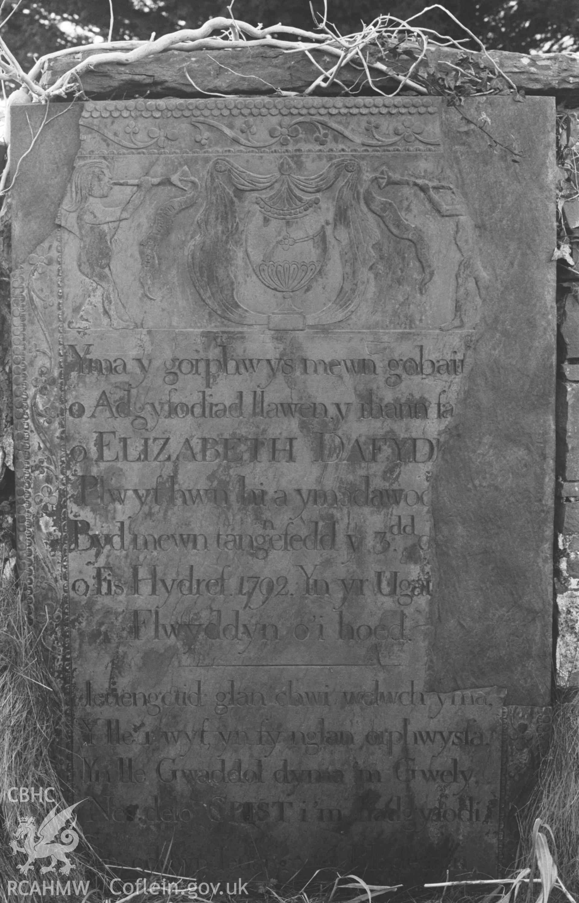 Digital copy of a black and white negative showing tombstone  near the south corner of the old graveyard at St Ursula's church, Llangwyryfon. Photographed by Arthur Chater on 30 December 1968. Looking south west from Grid Reference SN 5970 7047.