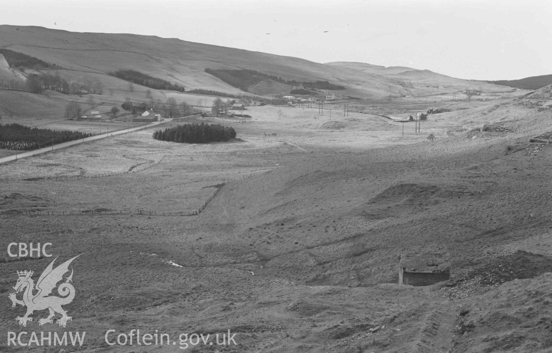 Digital copy of a black and white negative showing view from entrance to quarry behind Ffynnon-Cadno to Llywernog village and leadmine (right). Photographed by Arthur Chater on 2 April 1969. Looking west from Grid Reference SN 7401 8082.