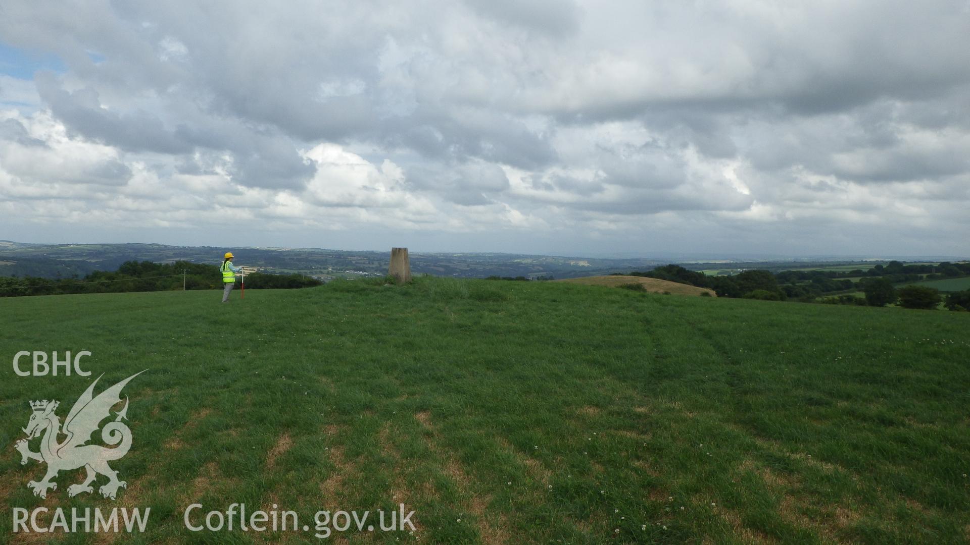 Trysor report plate 4:  Round barrow, PRN100717, with a concrete triangulation pillar on top of it. the barrow lies on the highest point of the rounded hill and 110 metres east of the closest turbine base, trench 1,  looking northeast.