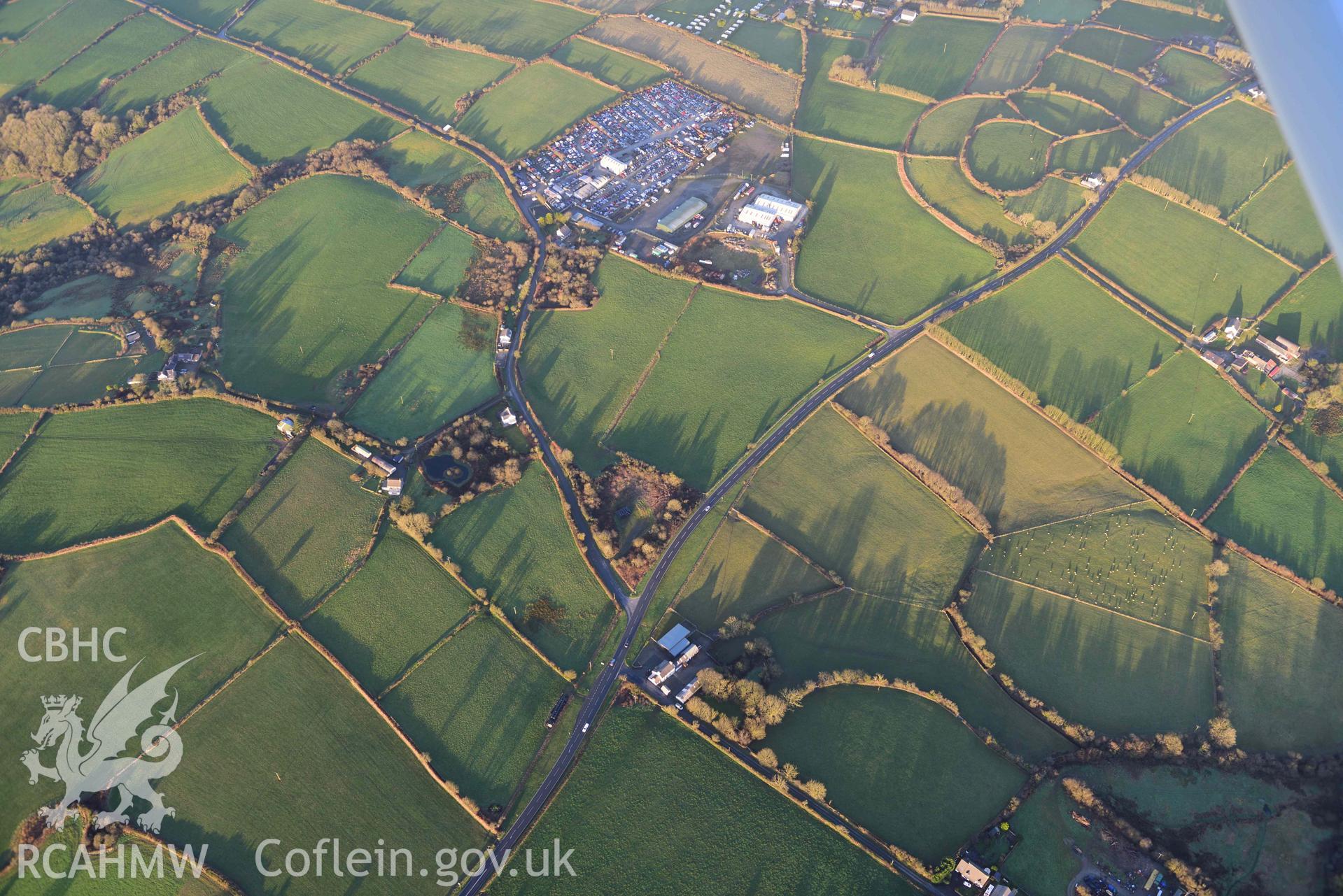 Oblique aerial photograph of Castell Nadolig hillfort, view from west in low winter light. Taken during the Royal Commission