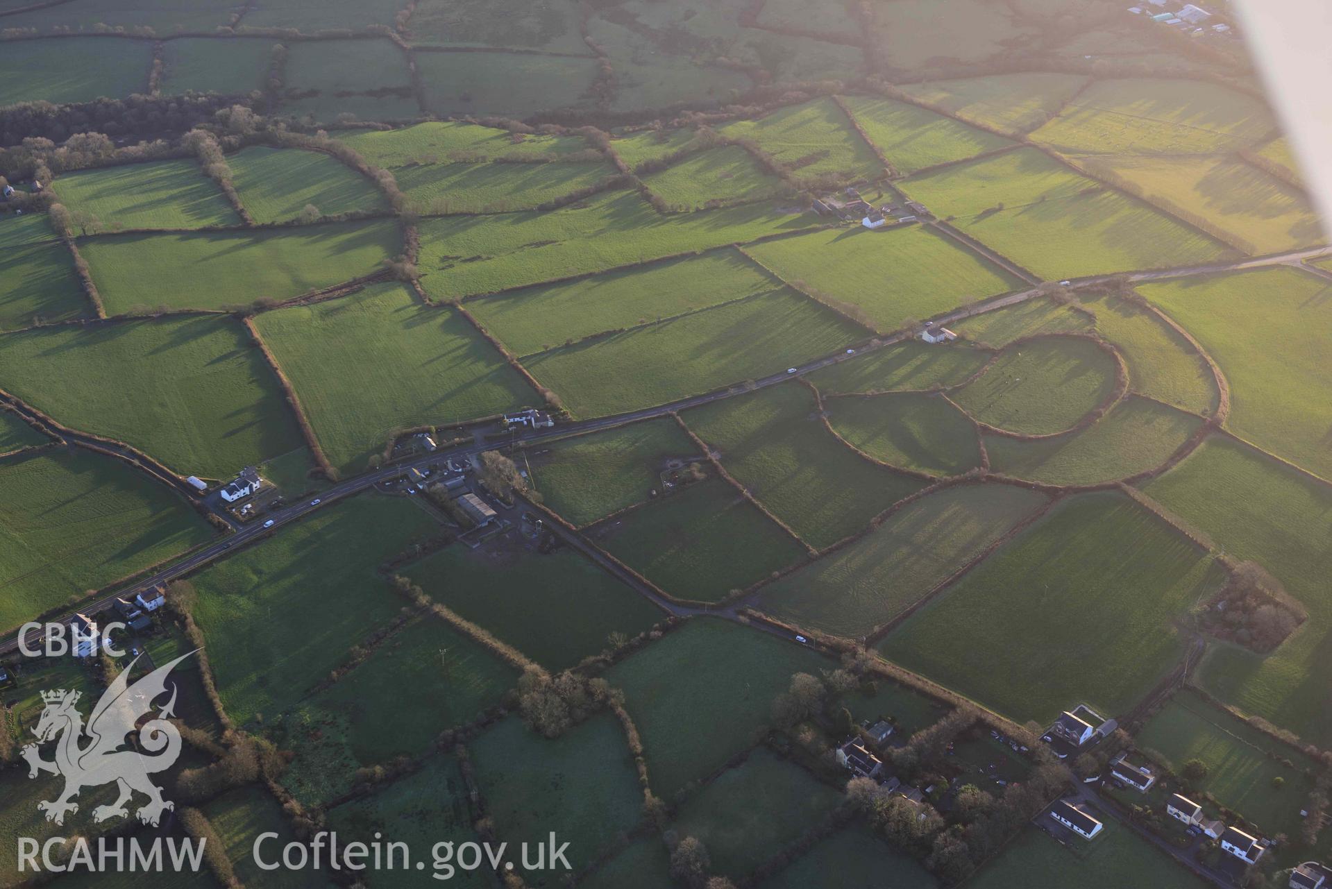 Oblique aerial photograph of Castell Nadolig hillfort, view from north east in low winter light. Taken during the Royal Commission