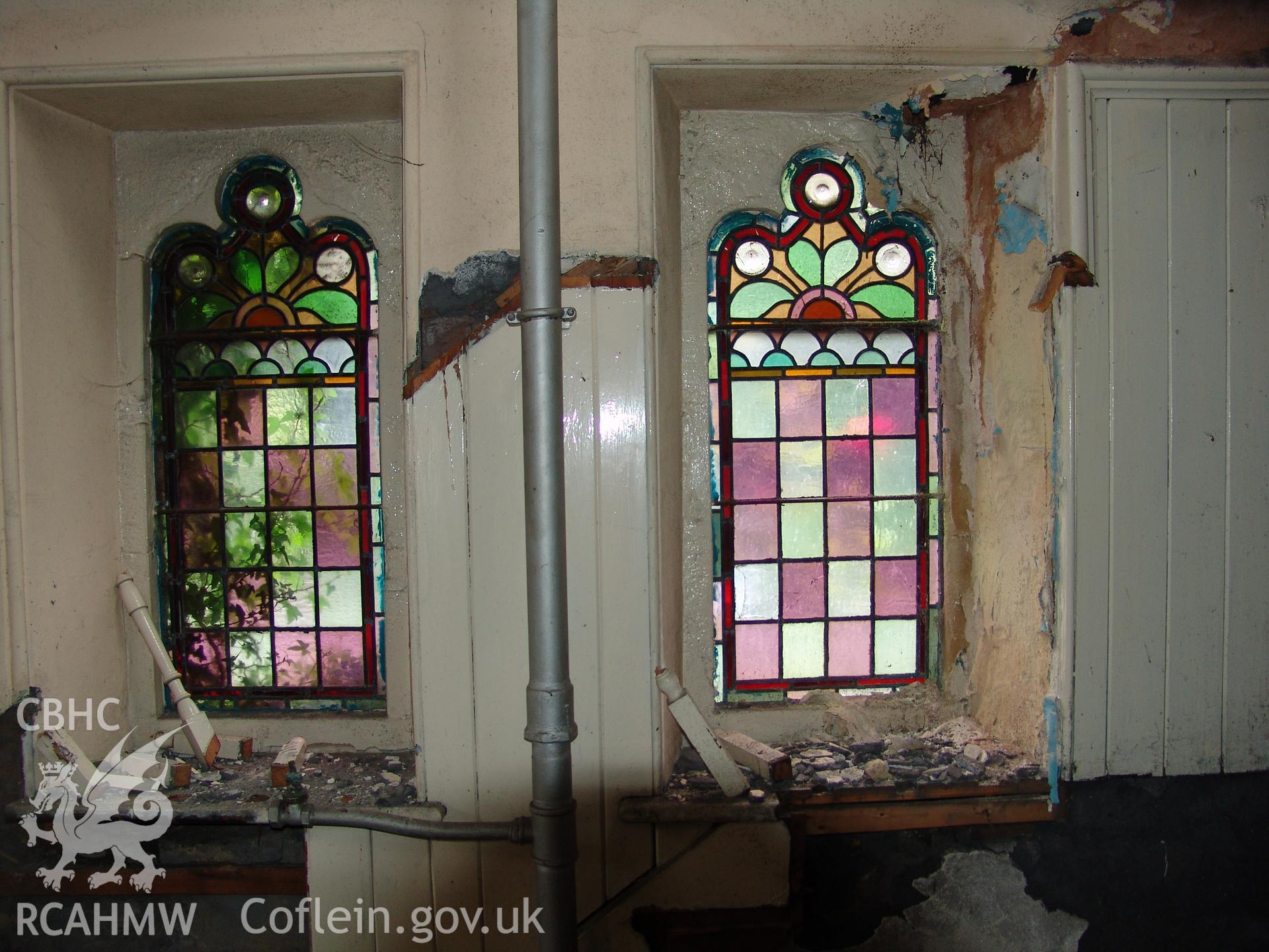 Photograph from a building recording survey: Zion Chapel, High Street, Newbridge, Gwent; internal view of stained glass in trefoil headed, twin lancet windows each side of chapel main door. Carried out by A. P. A. C. Ltd. in September 2008.