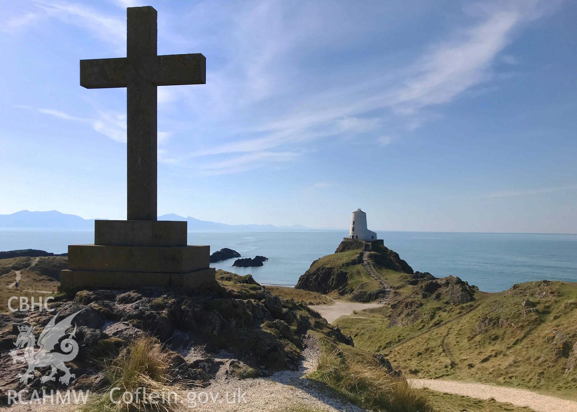 Digital photograph of Llanddwyn island lighthouse with cross in foreground. Produced by Paul Davis in 2020