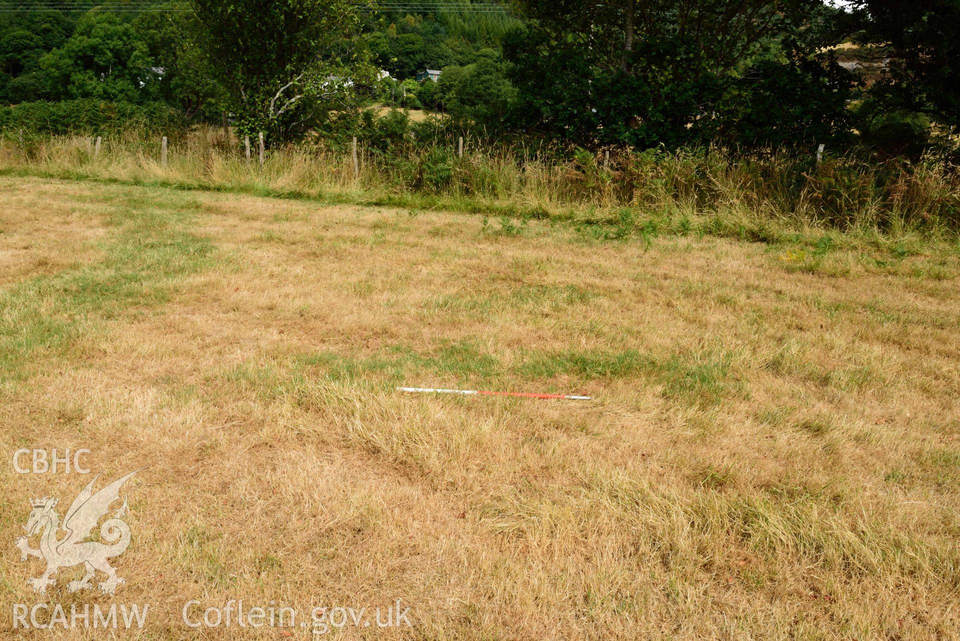 View of rectangular pit outside SE arc of concentric barrow, looking North East (scale 1m) at Dollwen barrow cemetery. Photographed by Toby Driver of RCHMAW during BBC filming of The One Show, 17 July 2018. Associated with Geophysical Survey of Pen y Wal, Dollwen Barrow, Goginan, commissioned by the RCAHMW and produced by Sumo Survey, 2021.