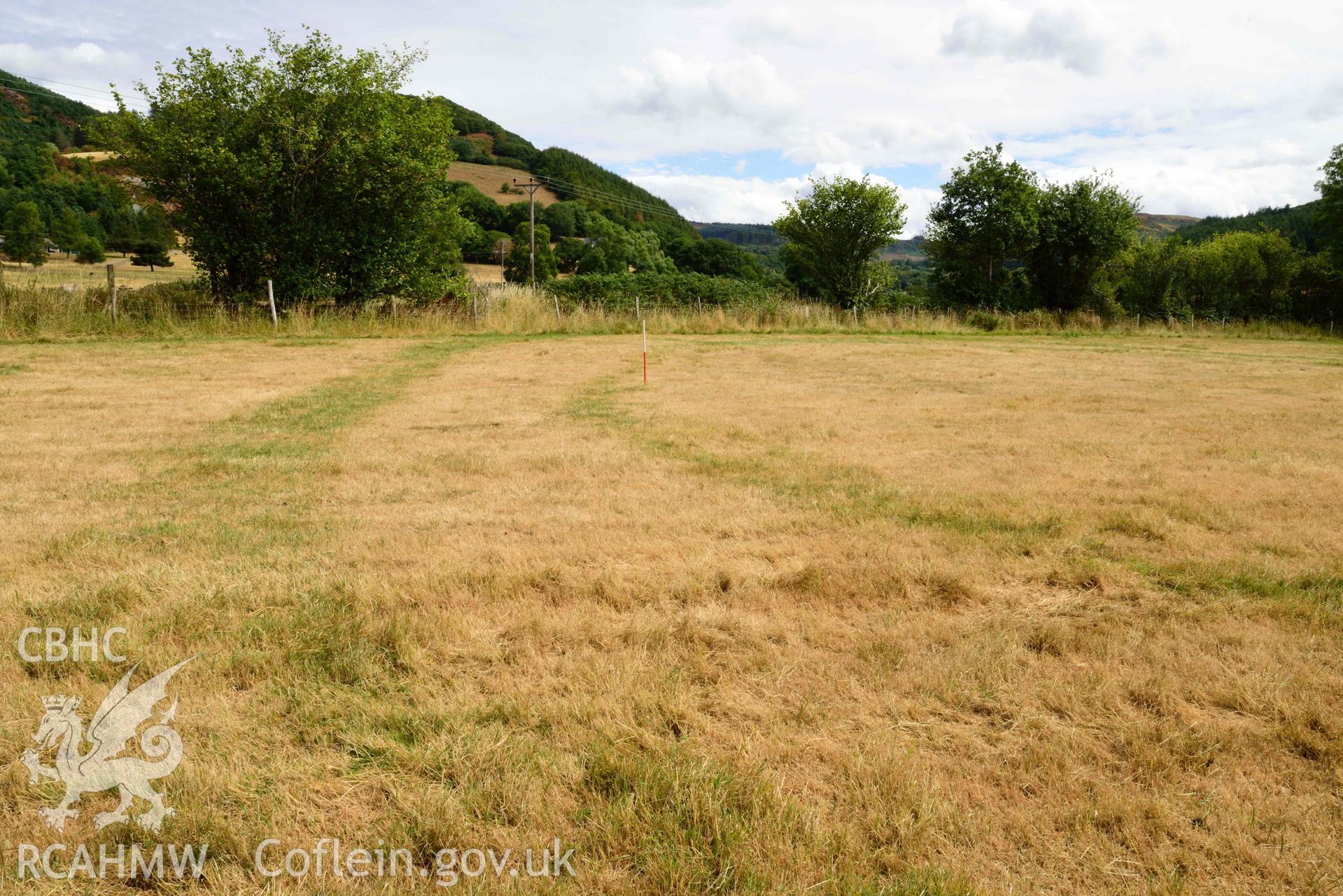 View of N arc of concentric barrow ditches, looking east (scale 1m) at Dollwen barrow cemetery. Photographed by Toby Driver of RCHMAW during BBC filming of The One Show, 17 July 2018. Associated with Geophysical Survey of Pen y Wal, Dollwen Barrow, Goginan, commissioned by the RCAHMW and produced by Sumo Survey, 2021.