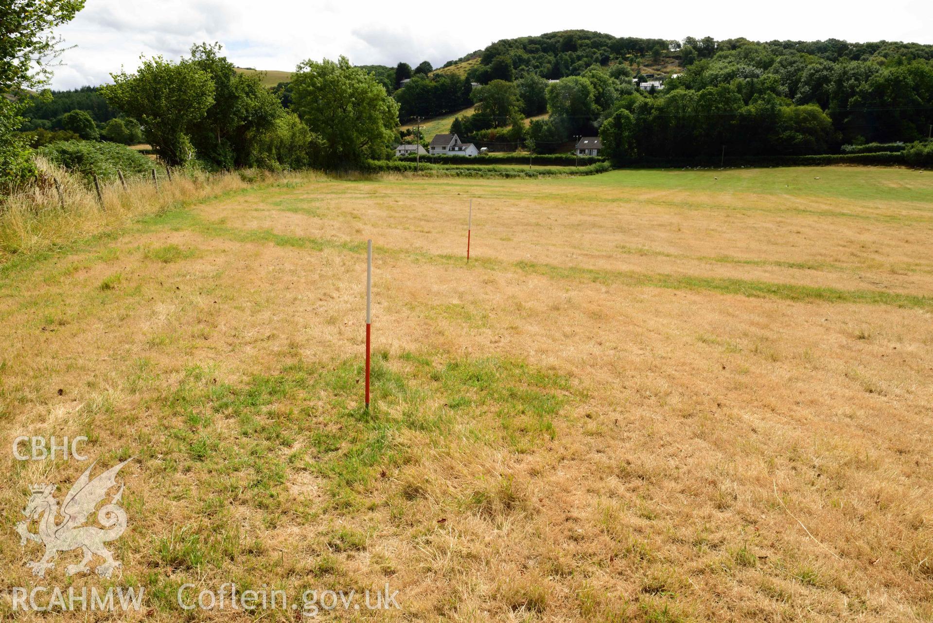 View of pit or post/stone hole to north-west of concentric barrow at SN 6868 8146, looking south (scale 1m) at Dollwen barrow cemetery. Photographed by Toby Driver of RCHMAW during BBC filming of The One Show, 17 July 2018. Associated with Geophysical Survey of Pen y Wal, Dollwen Barrow, Goginan, commissioned by the RCAHMW and produced by Sumo Survey, 2021.
