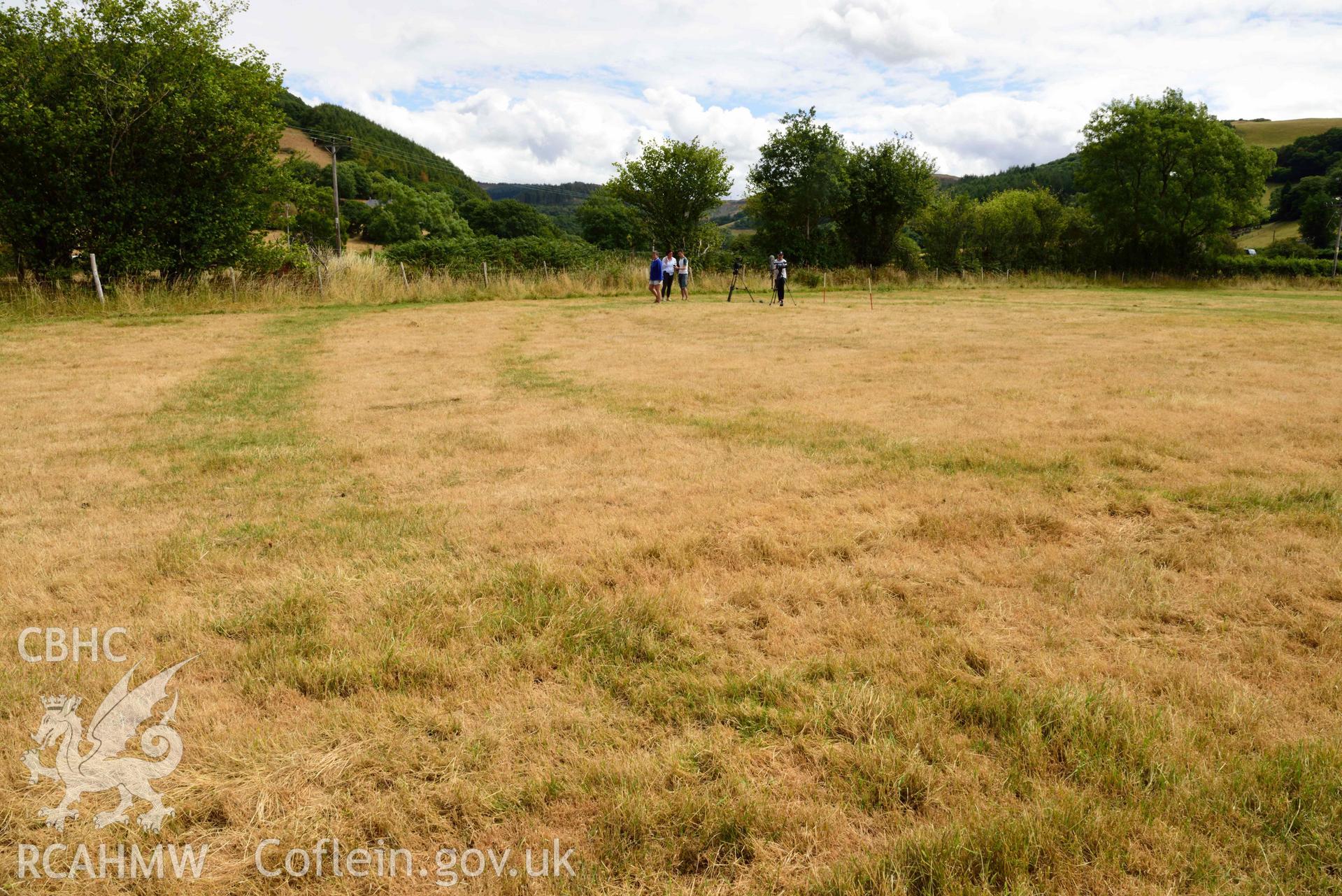 View of concentric north ditches of cropmarked barrow looking east at Dollwen barrow cemetery. Photographed by Toby Driver of RCHMAW during BBC filming of The One Show, 17 July 2018. Associated with Geophysical Survey of Pen y Wal, Dollwen Barrow, Goginan, commissioned by the RCAHMW and produced by Sumo Survey, 2021.